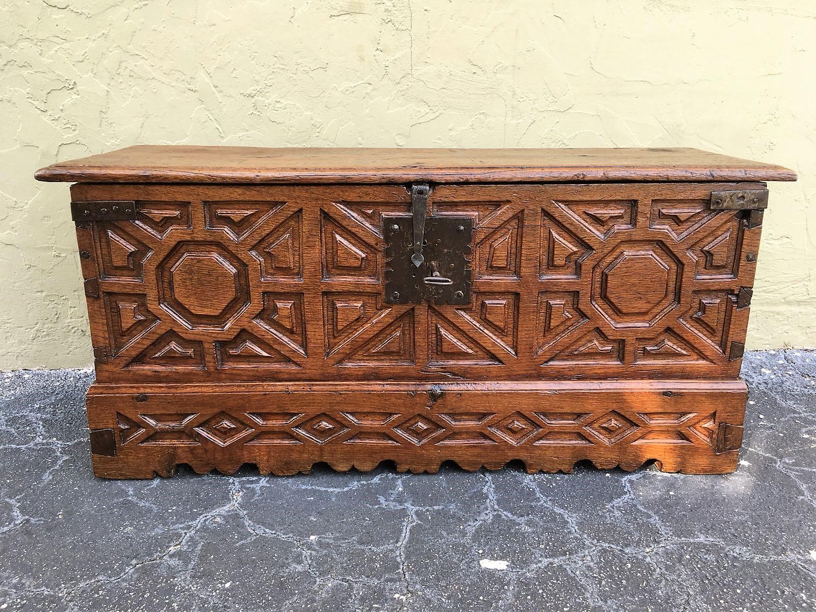 A Spanish 18th century wood coffer. This Spanish trunk from the 18th century features beautifully visible dovetail joints down each corner side and a scalloped skirt which is adorned with geometrical carvings. The trunk's interior offers a large