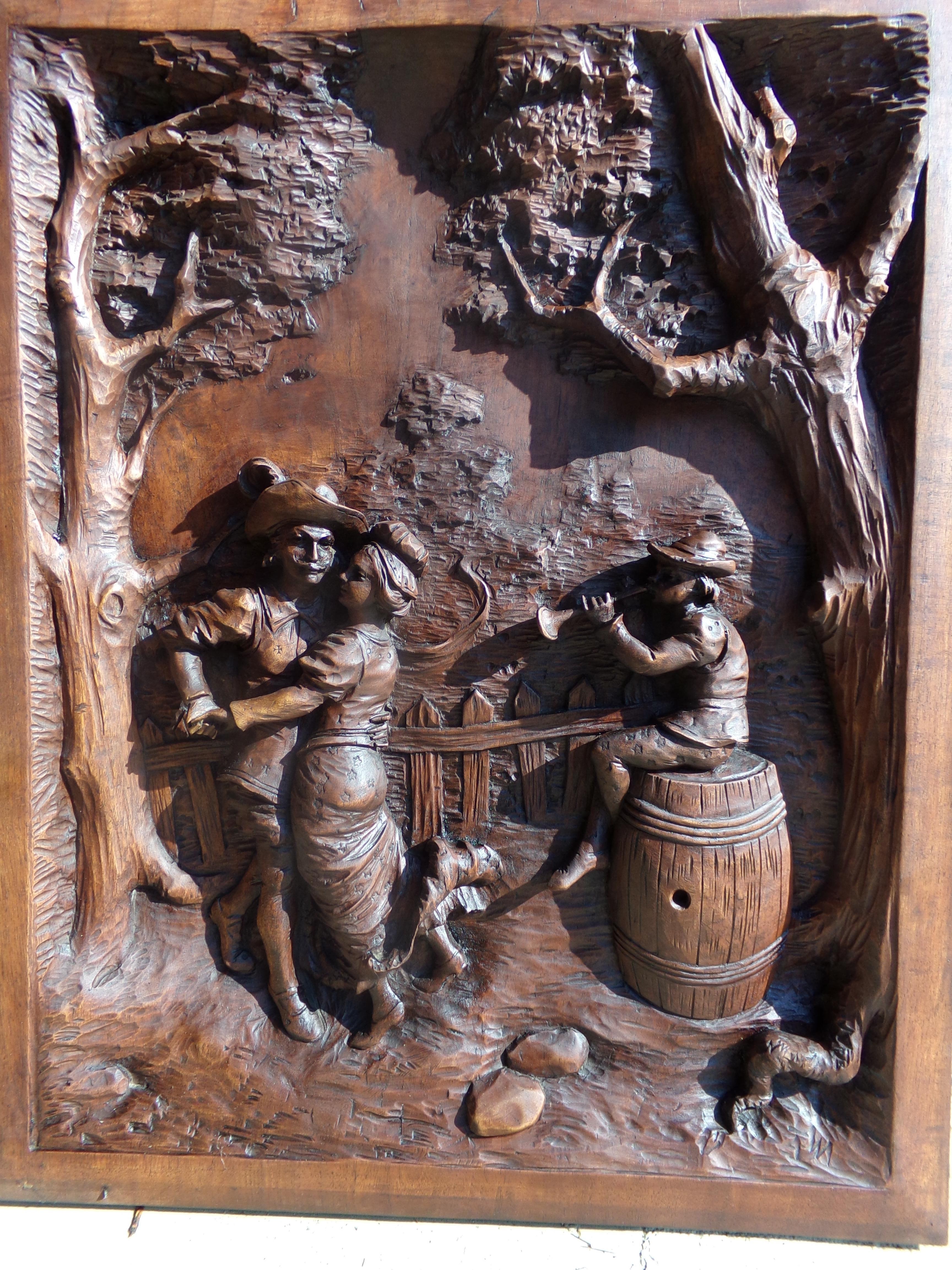 A stunning large hand carved Black Forest Style Walnut panel depicting a stylised 17th century country village scene with a couple dancing and a musician, This beautiful panel is signed with the initials TW we are trying to research the name.
Size