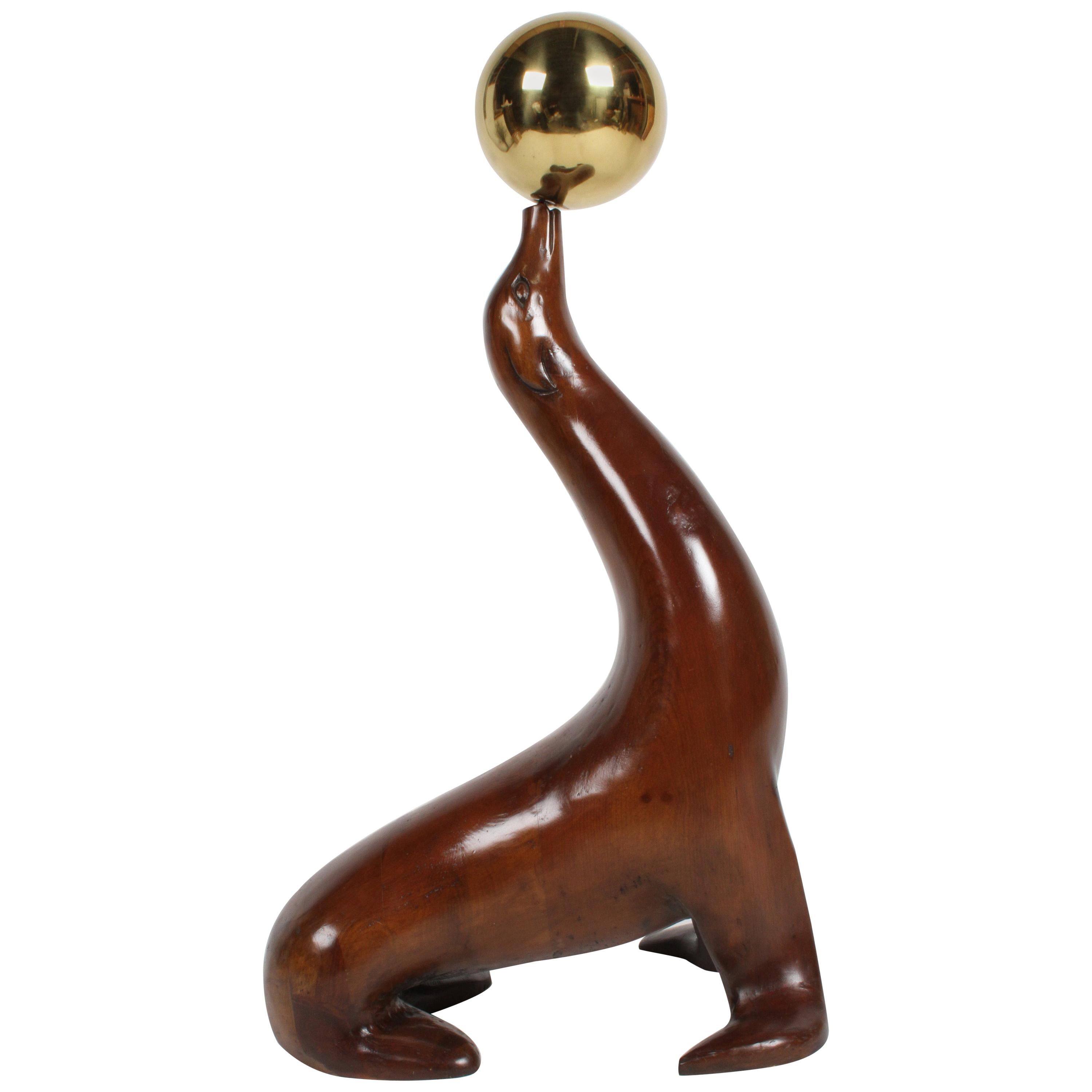 Grand lion ou sceau de mer sculpté en bois d'orme balançant une boule de laiton