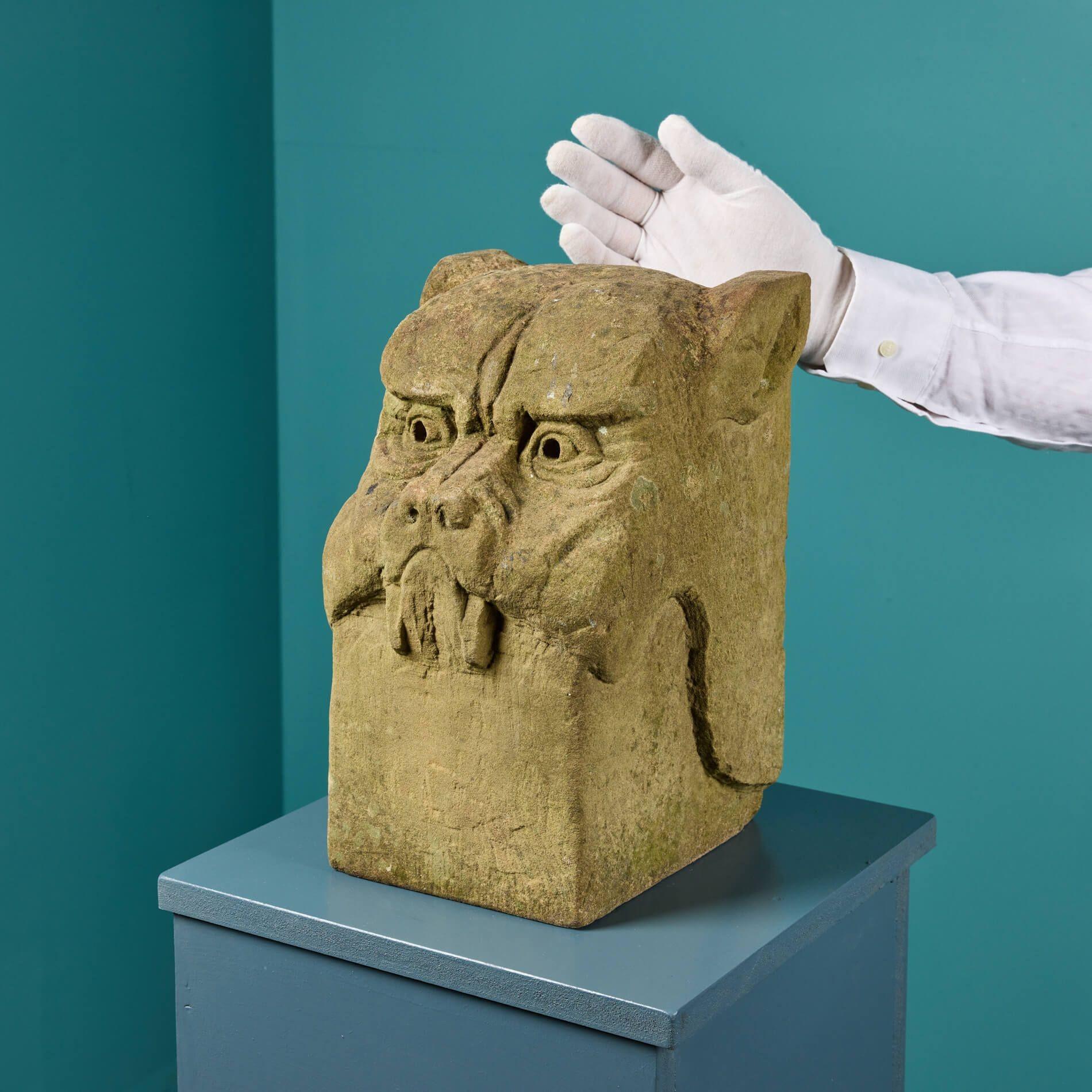 Une statue de chien gargouille stylisée, sculptée de manière expressive dans la pierre de York. Datant de la fin du XIXe siècle ou du début du XXe siècle, cette tête de chien a plus de 120 ans et présente donc une surface naturellement altérée par