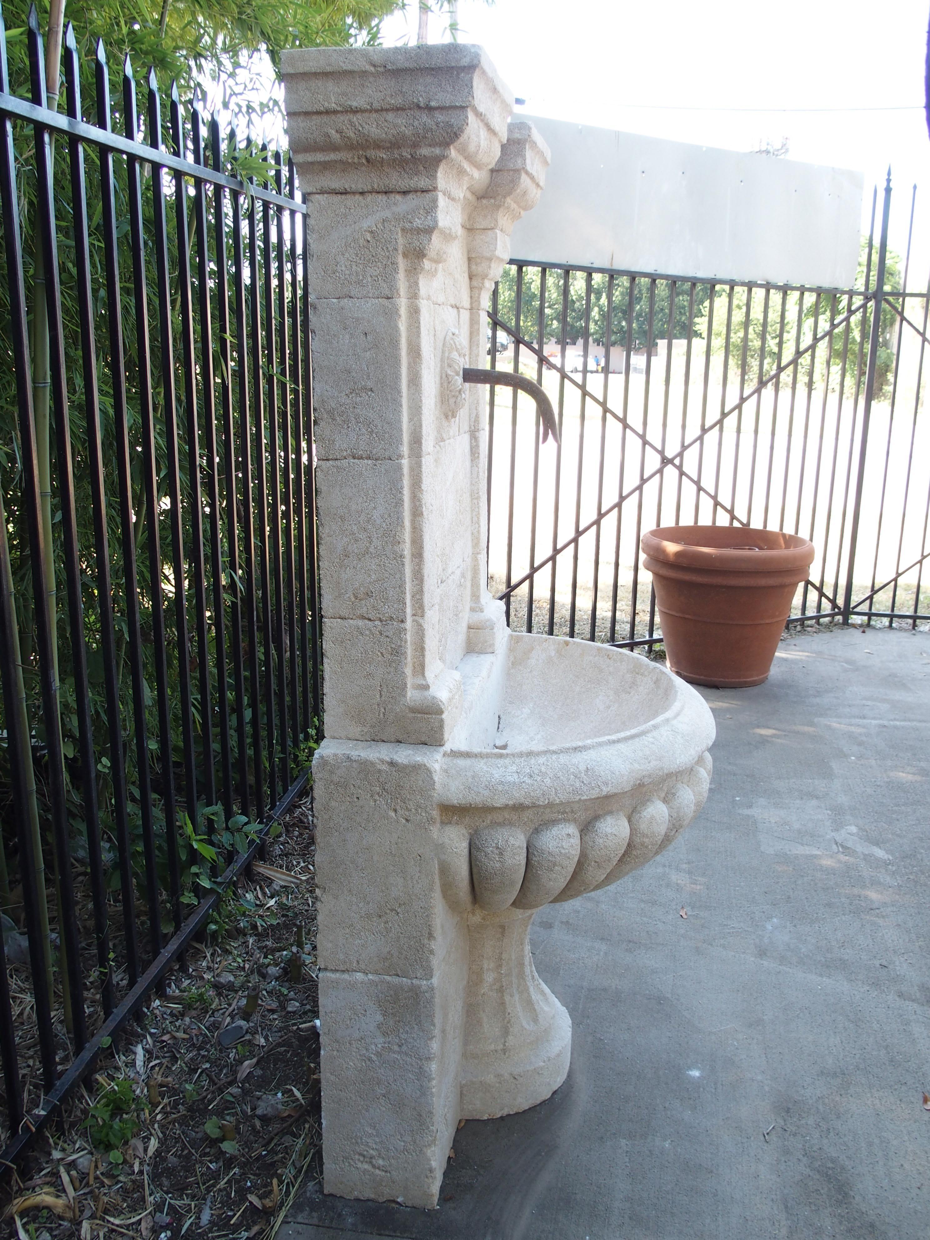 This stunning, hand carved wall fountain from France has been designed with architectural ornamentation. There is a crown molding with pilaster capitals and pilasters on either side ending in a plinth at the lobed basin. It is handmade from