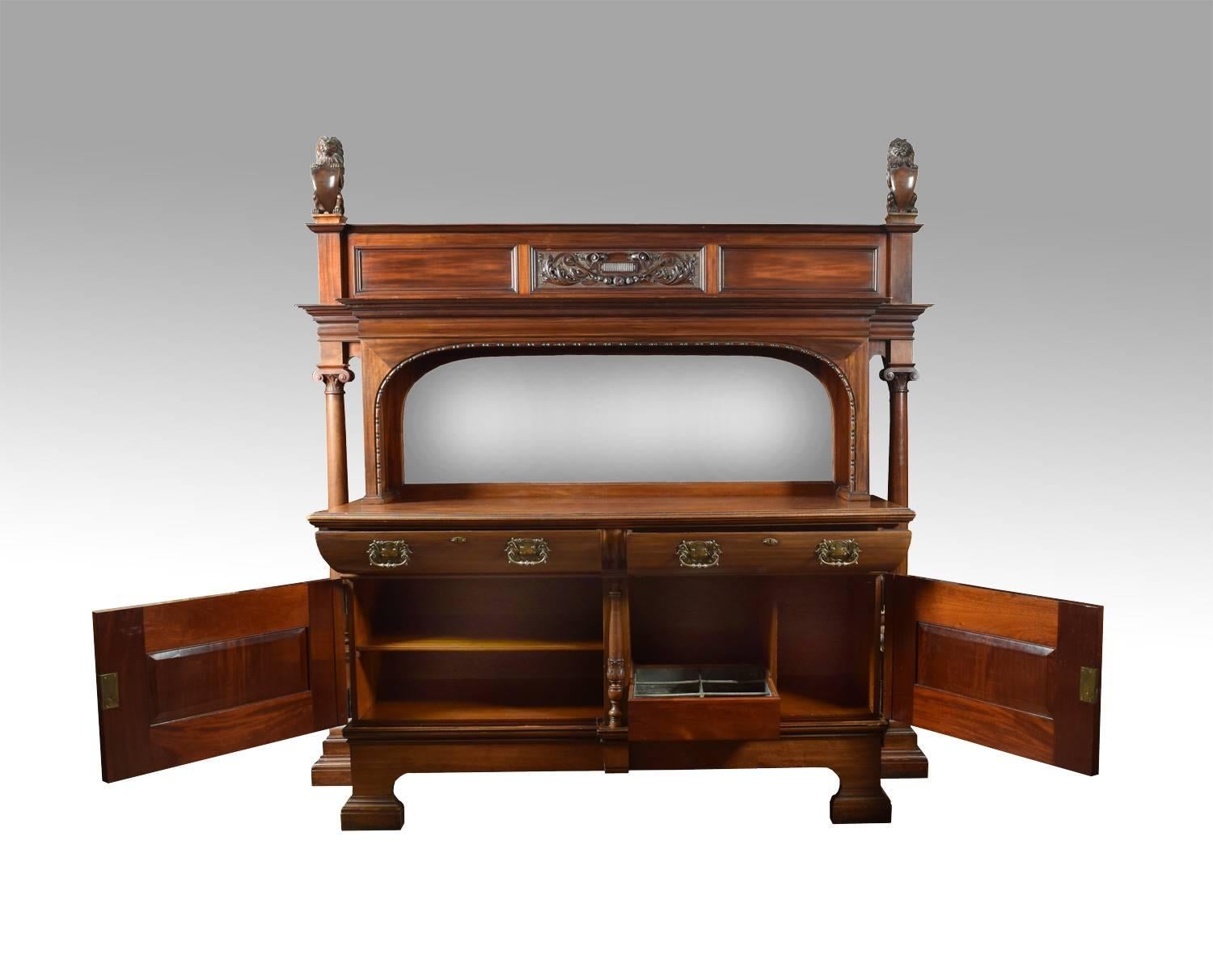 Very large walnut 19th century sideboard. The shaped beveled mirror back surmounted with lion finials and flared cornice supported on two circular turned columns with scrolling capitals.
The base section with two curved freeze draws with brass