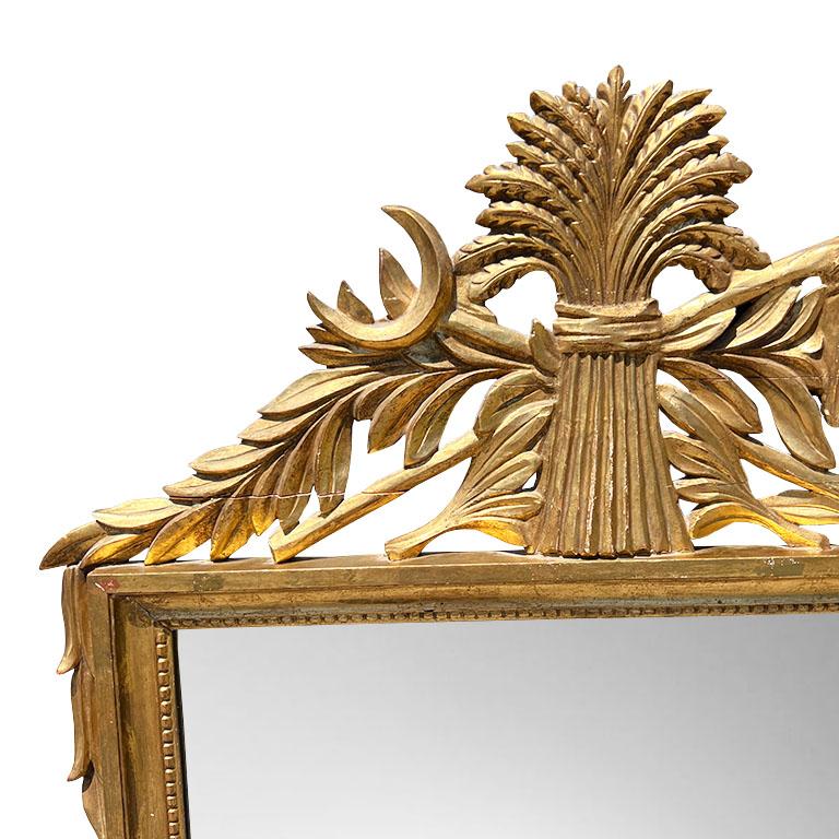 A monumental Regency gilt-carved wood wall mirror with a sheaf of wheat and moon motif. This extra large mirror will be fabulous hung on a wall above a mantle or in an entryway. The body of the mirror is rectangular and surrounded by a gilt