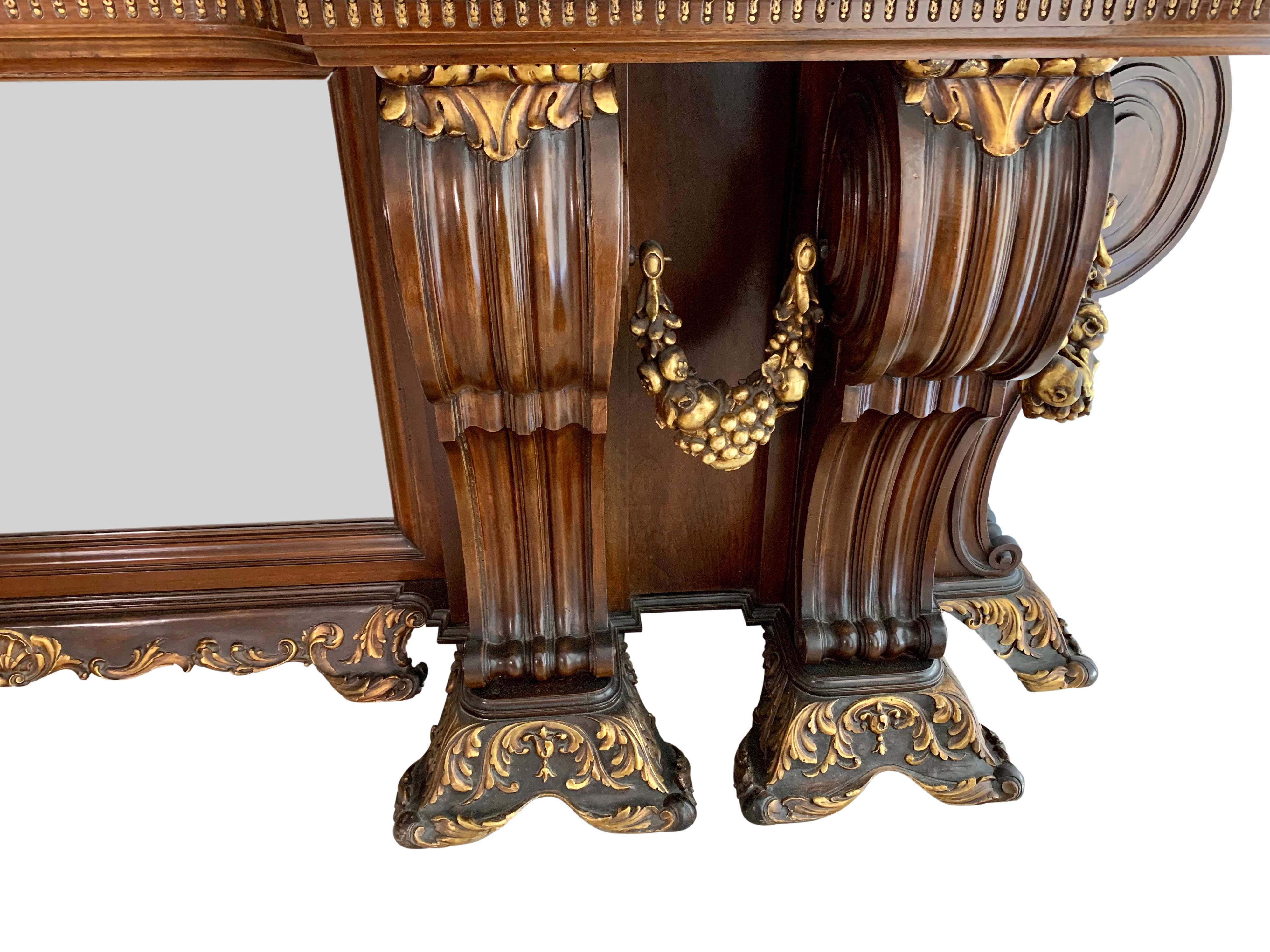 An impressive and large-scale Italian Neoclassical style brown and parcel gilt hand carved wood console table. The white marble top with delicate veins above six massive curved legs flanked by four carved giltwood wreaths and centered by a