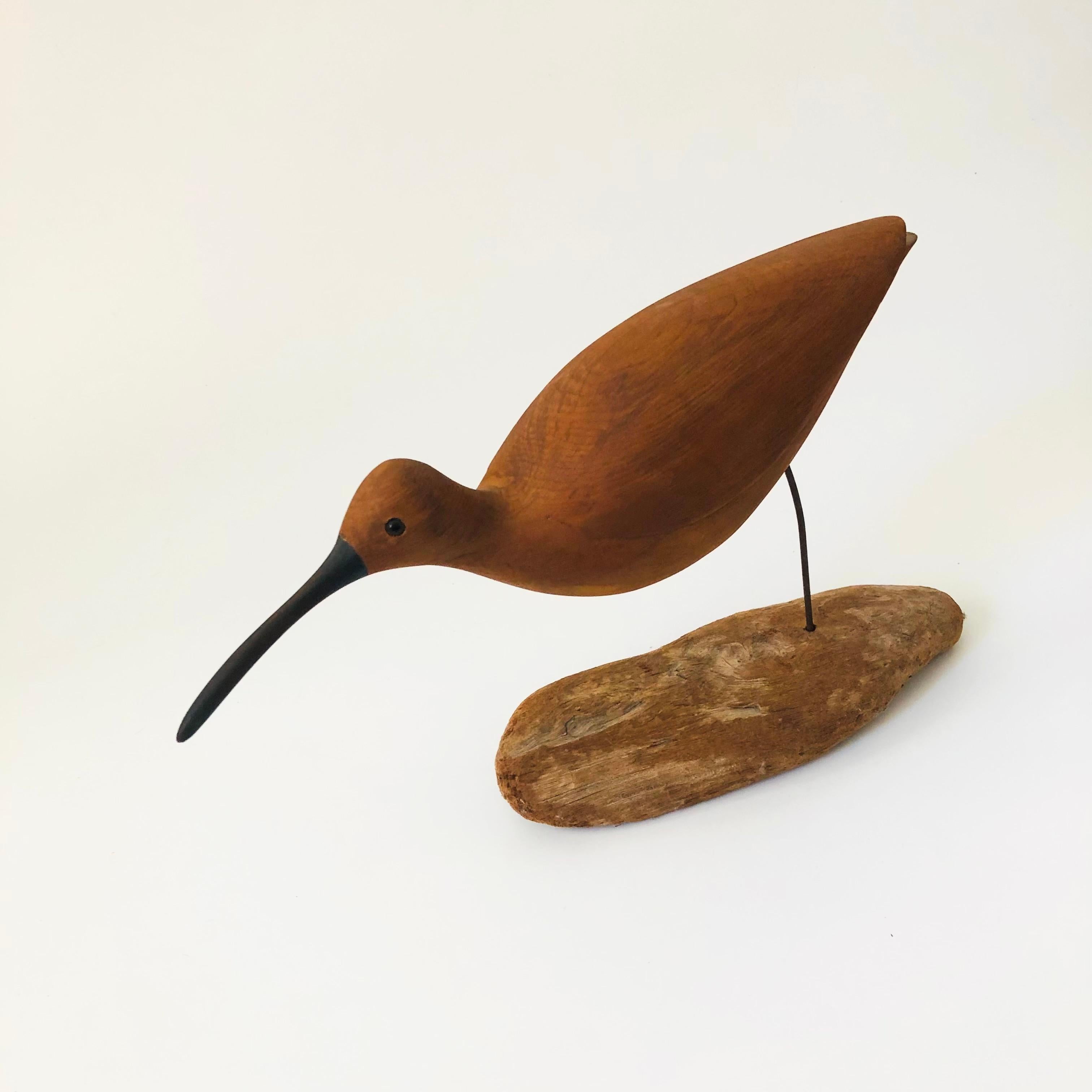 A beautiful vintage hand carved wood bird sculpture. Features a sandpiper bird, carved smooth, connected to a natural wood base with a metal rod. Stamped 