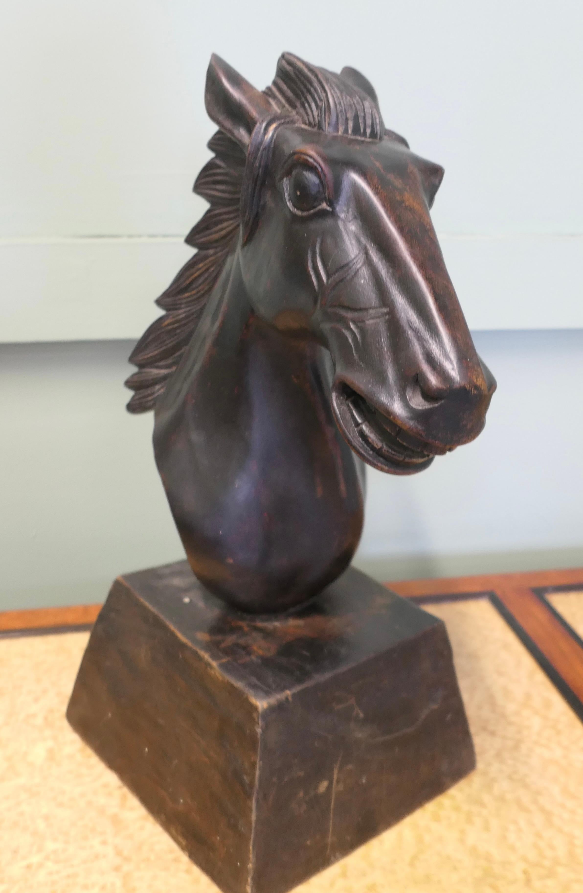 Grande tête de cheval en bois sculpté 

Ce superbe personnage est sculpté dans une seule pièce de bois et est monté sur un socle en bois. Il présente une bonne patine foncée. 
La tête est en très bon état avec une légère usure de la patine car il