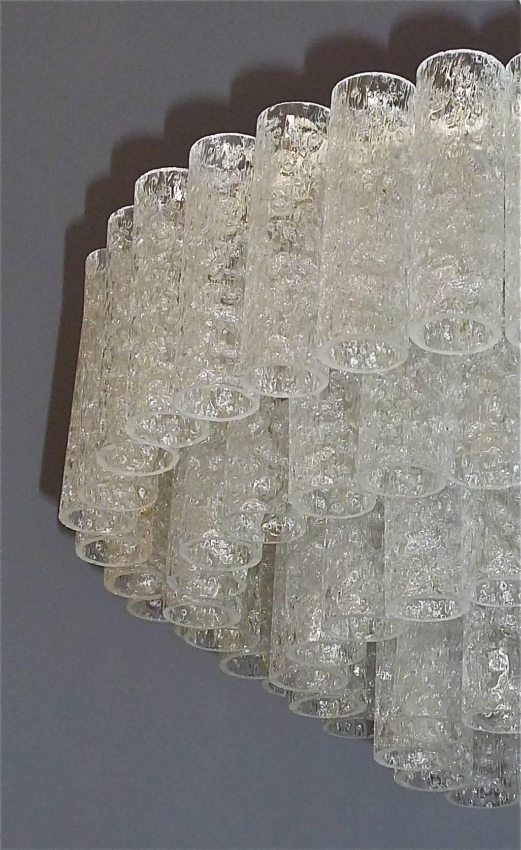 A large flush mount chandelier by Doria, Germany, circa 1960s. It has four cascading tiers with lots of textured ice glass tubes hanging on a white enameled metal light fixture. It takes ten x E14 standard screw bulbs to illuminate. The wiring is