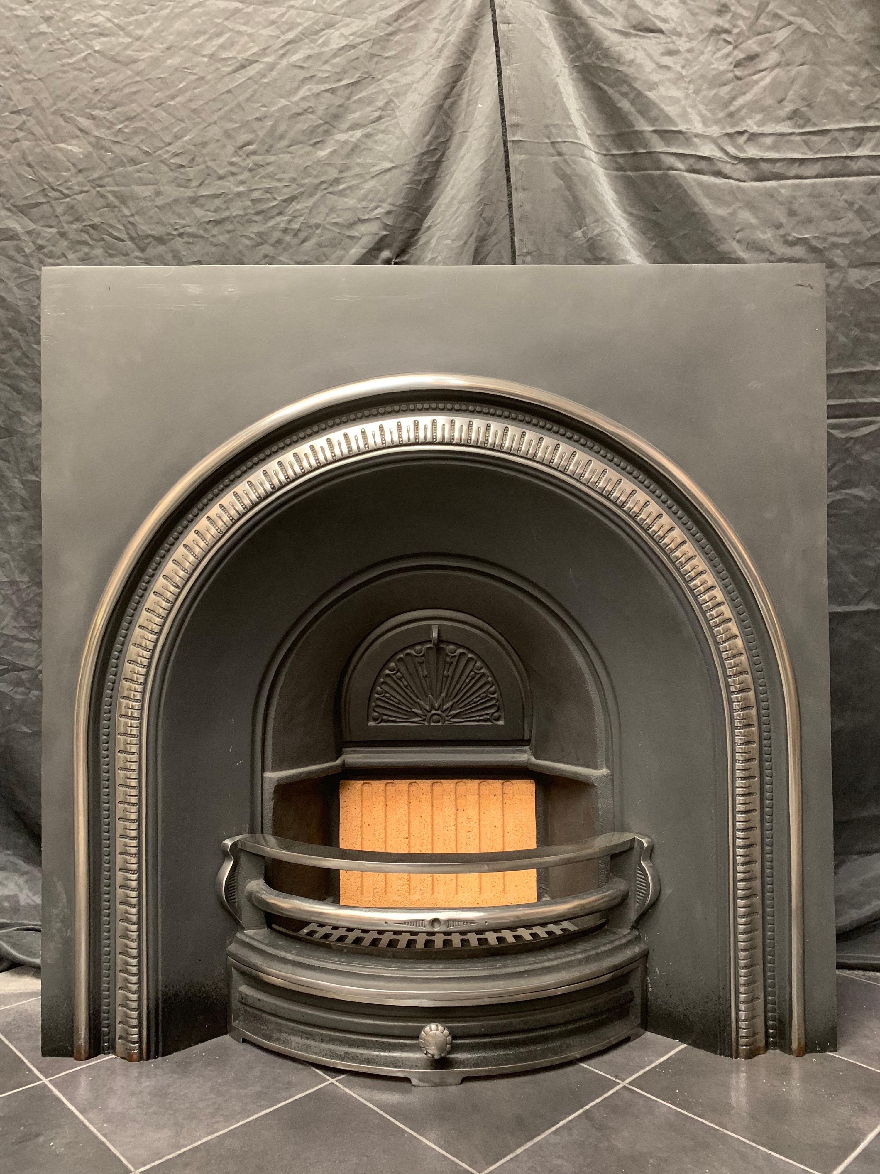 A large and wide Victorian style cast iron fireplace insert of good proportions, a polished outer frame with its original damper plate, a three barred fire grate and ash pan door with a new fire brick to the rear. 

English, circa 1940.