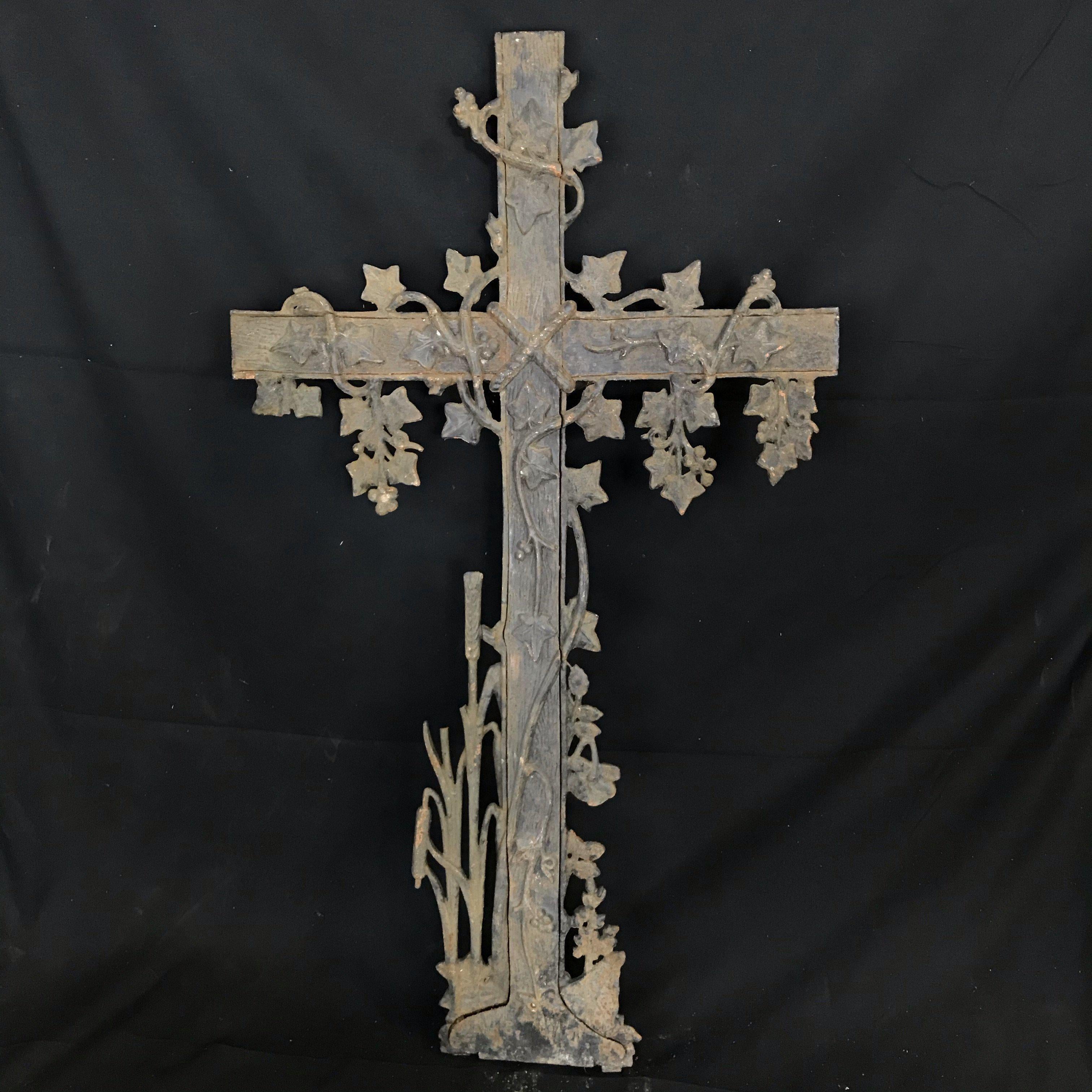 Cette croix en fer française d'antiquités présente un motif décoratif de feuillage avec des roses et du lierre sur le dessus, les bras et la base. Jesus est représenté sur la croix drapée de raisins et de détails en lierre. Cette sculpture