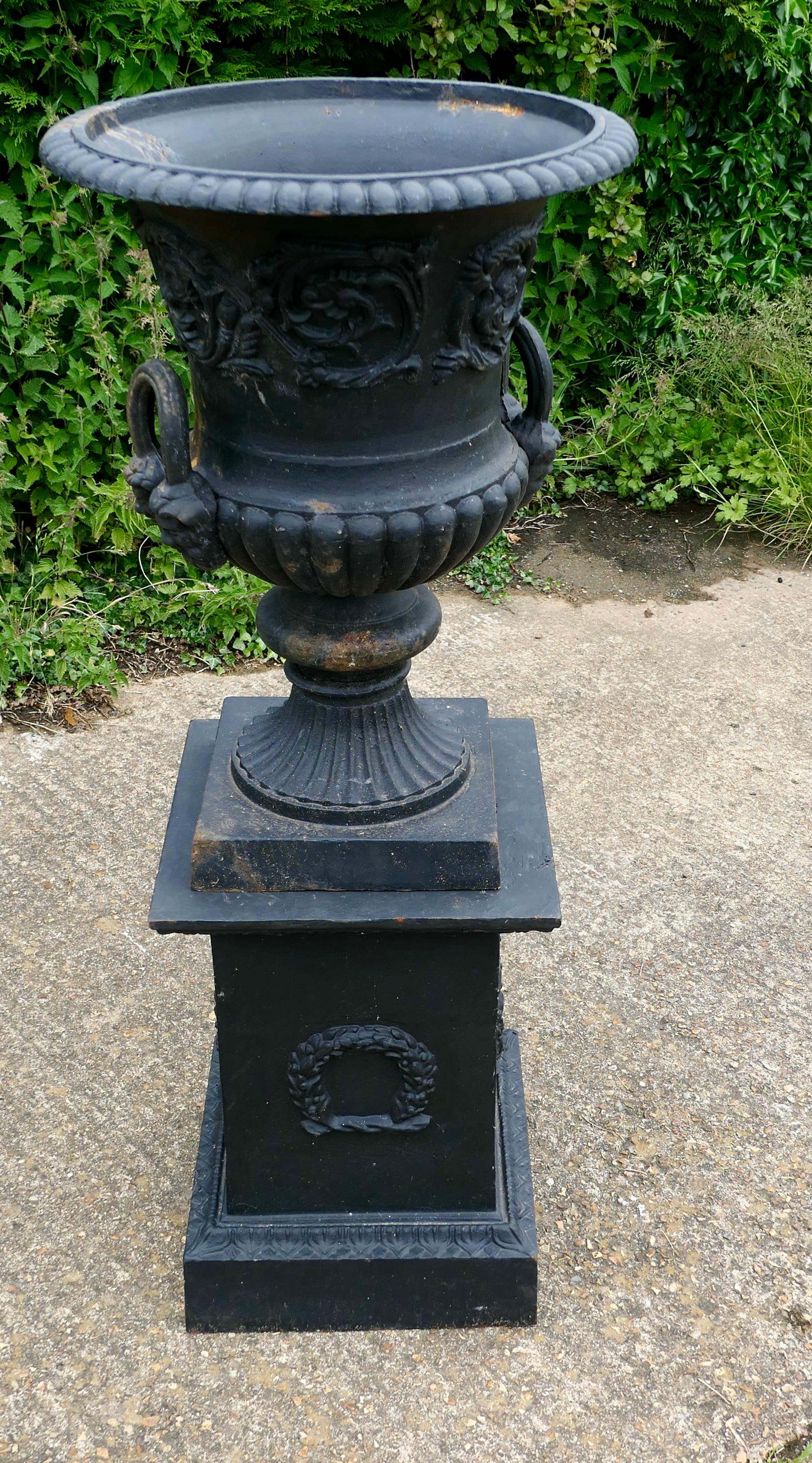Large cast iron urn, garden planter

This is a superb large garden urn on a plinth, the urn is in cast iron with a classical flower pattern and it has lions mask handles.
The plinth is decorated with laurel wreath on every side.
The urn and