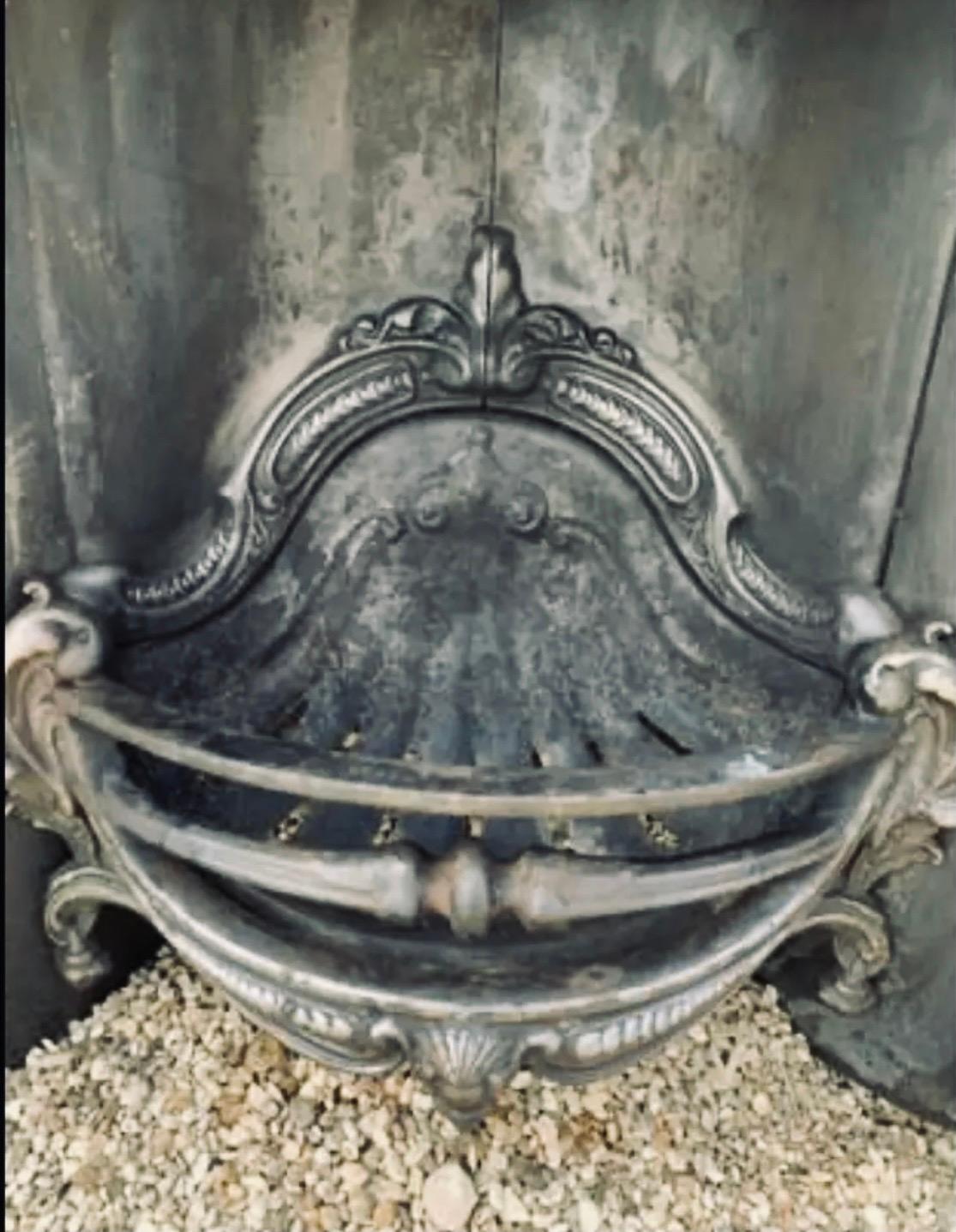 A large and substantial cast iron Victorian manner horseshoe shaped insert. A generous back plate supporting a high relief decorative frame, the scallop shaped fire back with scallop shaped grate, complete with its original ash pan cover.

Photos