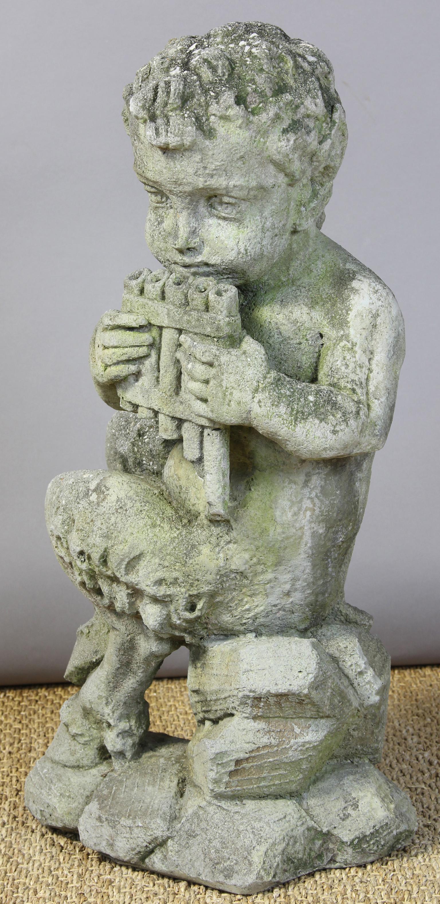 A very charming mid-20th century cast stone garden ornament of a mischievous flute-playing pan perched on a jagged crop of rocks.