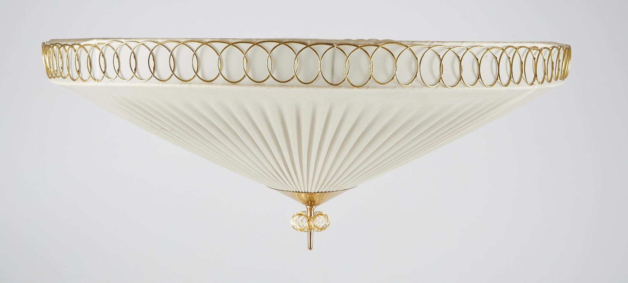 A ceiling light designed by Paavo Tynell, produced by Idman Oy, Model K5-27. Finland , circa 1950th.

Polished brass and pleated plastic lampshade. Two lighting sockets.. Diameter 27.6″, height about 12″.

Existing wires, rewiring available upon