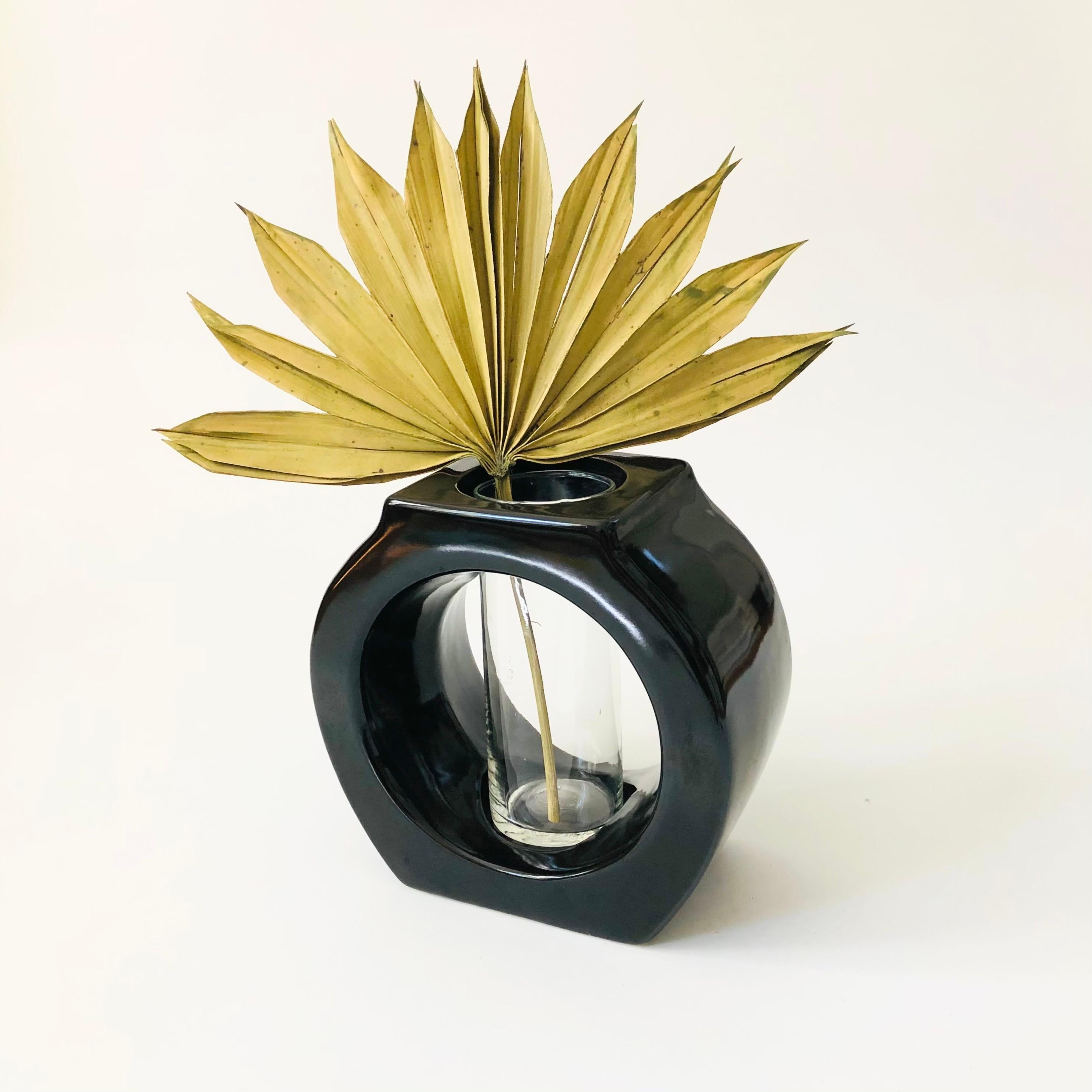 Un grande vaso scultoreo vintage. Presenta una fiala di vetro al centro di un supporto in ceramica nera lucida. Perfetto per esporre composizioni floreali o come vaso di propagazione.

