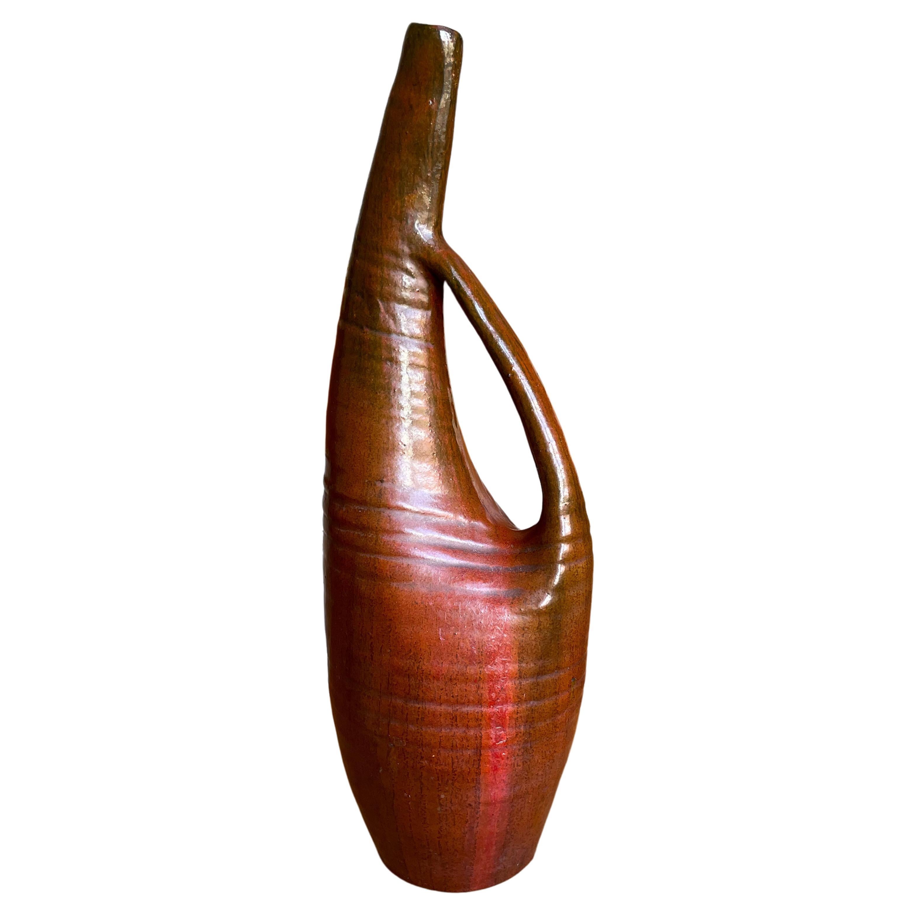 Tall Scandinavian ceramic art statement piece. Handmade organic modern asymmetrical sculptural textured bottle vase glazed in warm caramel brown, maroon and bright red colors. Curved neck, slender handle. Beautiful vintage condition. 
Scandinavia,
