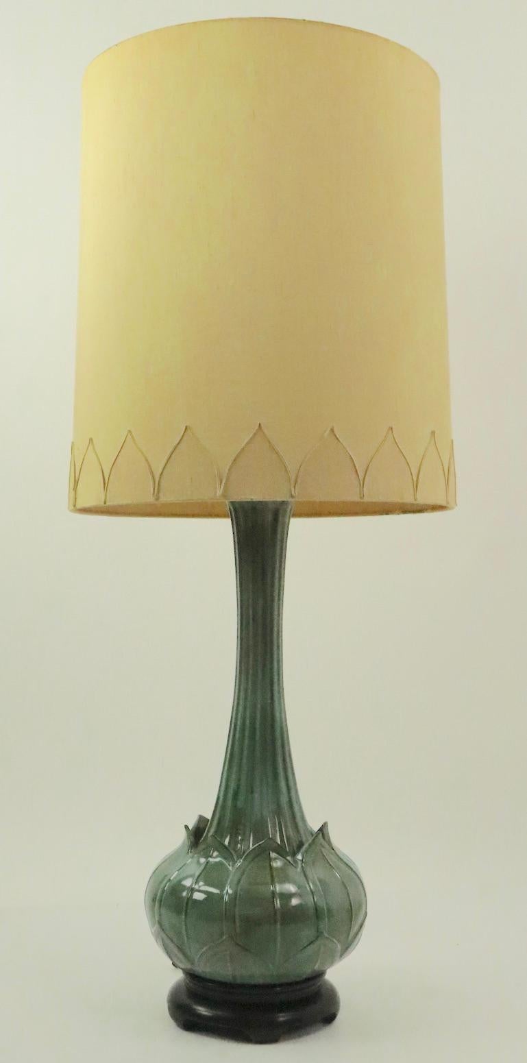Chic and stylish ceramic table lamp of impressive scale in the Asian taste. The lamp has a Lotus form body with an exaggerated elongated neck, on a black wooden base. Original drum shade included, features decorative Lotus leave trim to mach the
