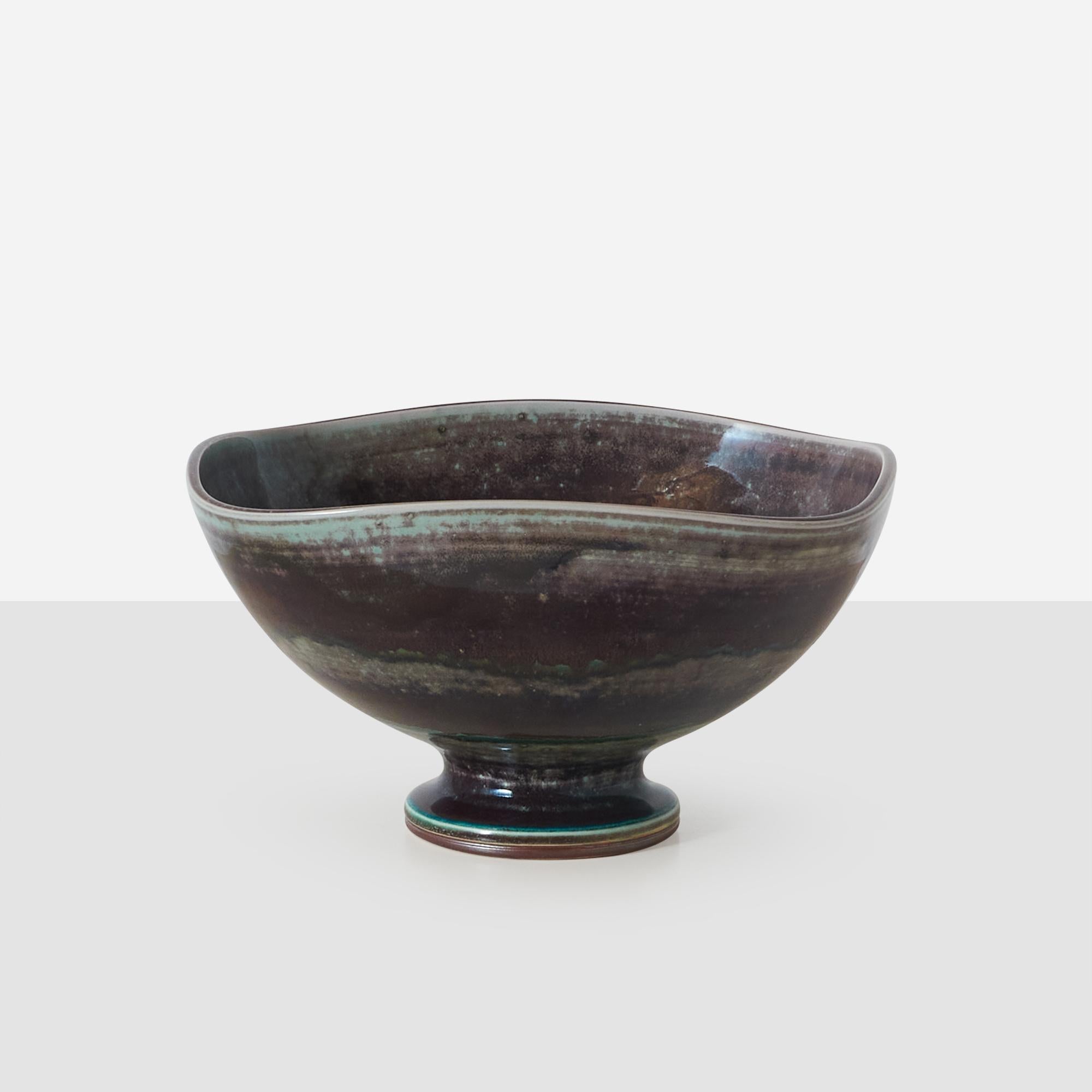 A large and unique organic shaped footed ceramic bowl in hues of blue, green and brown by Berndt Friberg for Gustavsberg. Incised Friberg signature, 1974 and Gustavsburg studio hand on the base.