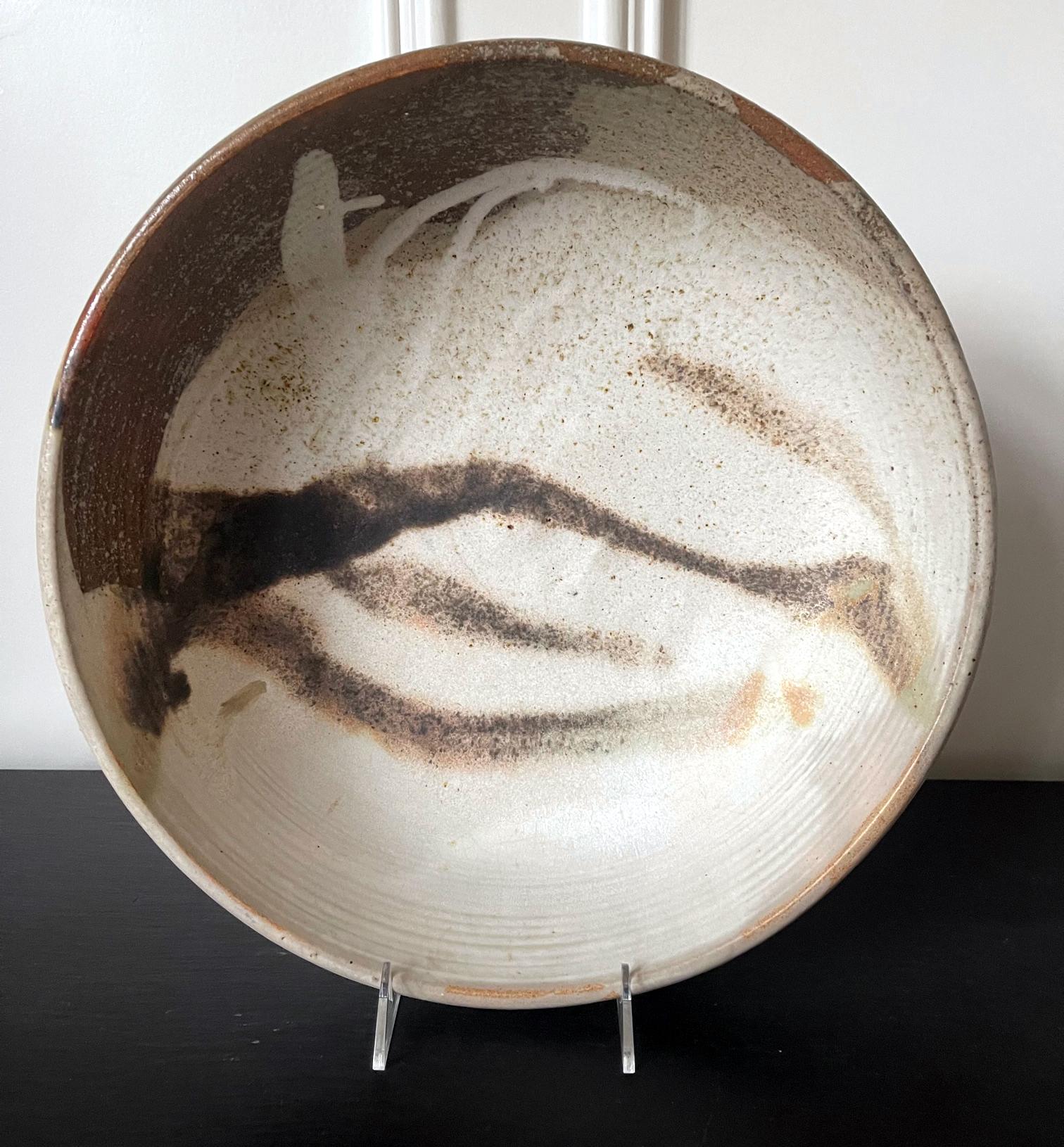 Eine große Keramikschale der japanisch-amerikanischen Künstlerin Toshiko Takaezu (Amerikanerin, 1922 - 2011). Die tiefe Form der Schale mit ihrem robusten, dickwandigen Korpus, der von einem kurzen, runden Fußring getragen wird, ist als