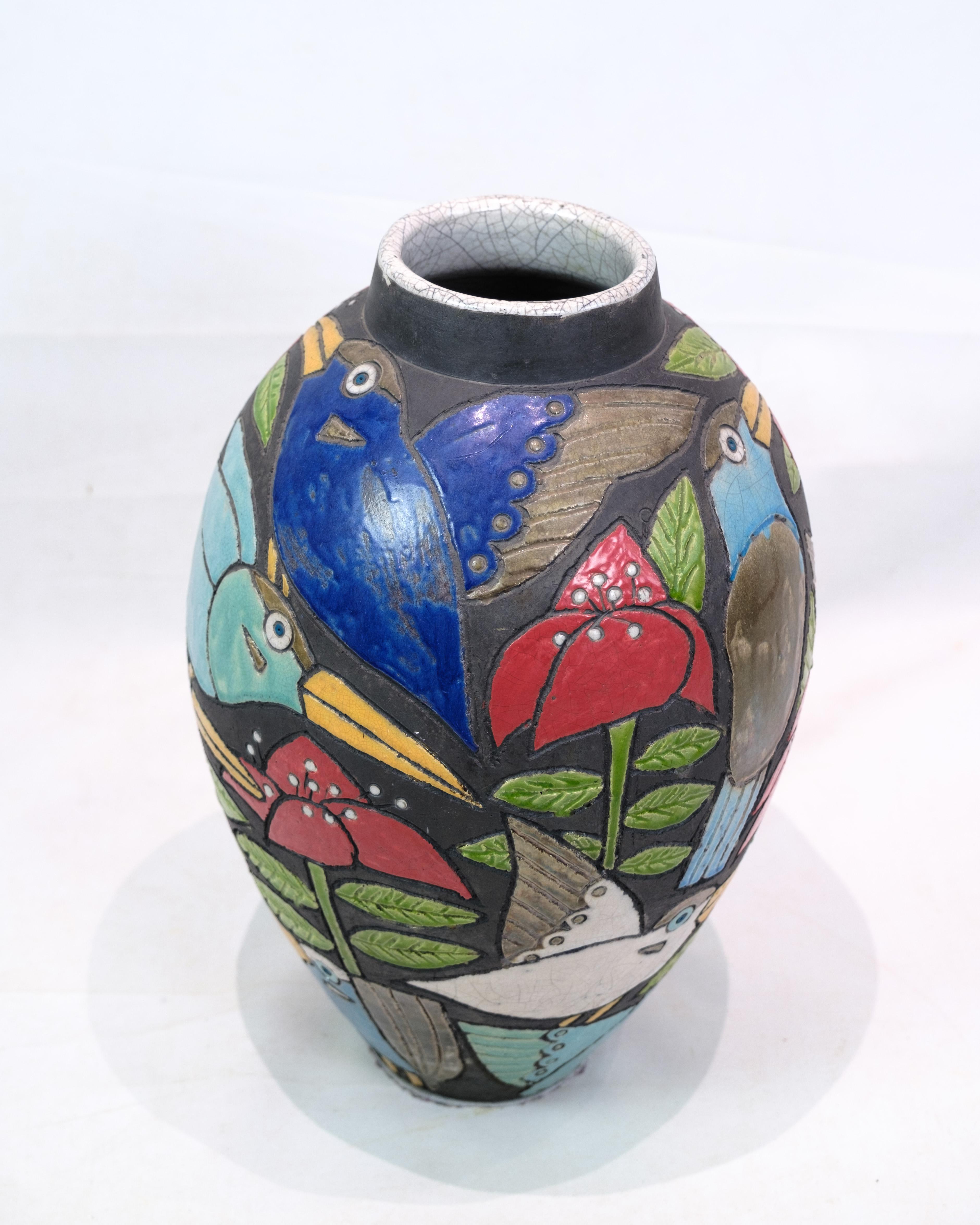 Diese große Bodenvase aus Keramik ist ein wunderschönes, verziertes Objekt, verziert mit Motiven von Vögeln und Blumen in bunten Farbtönen. Die von Dorte Friis entworfene Vase zieht mit ihren lebhaften und lebendigen Details sofort die