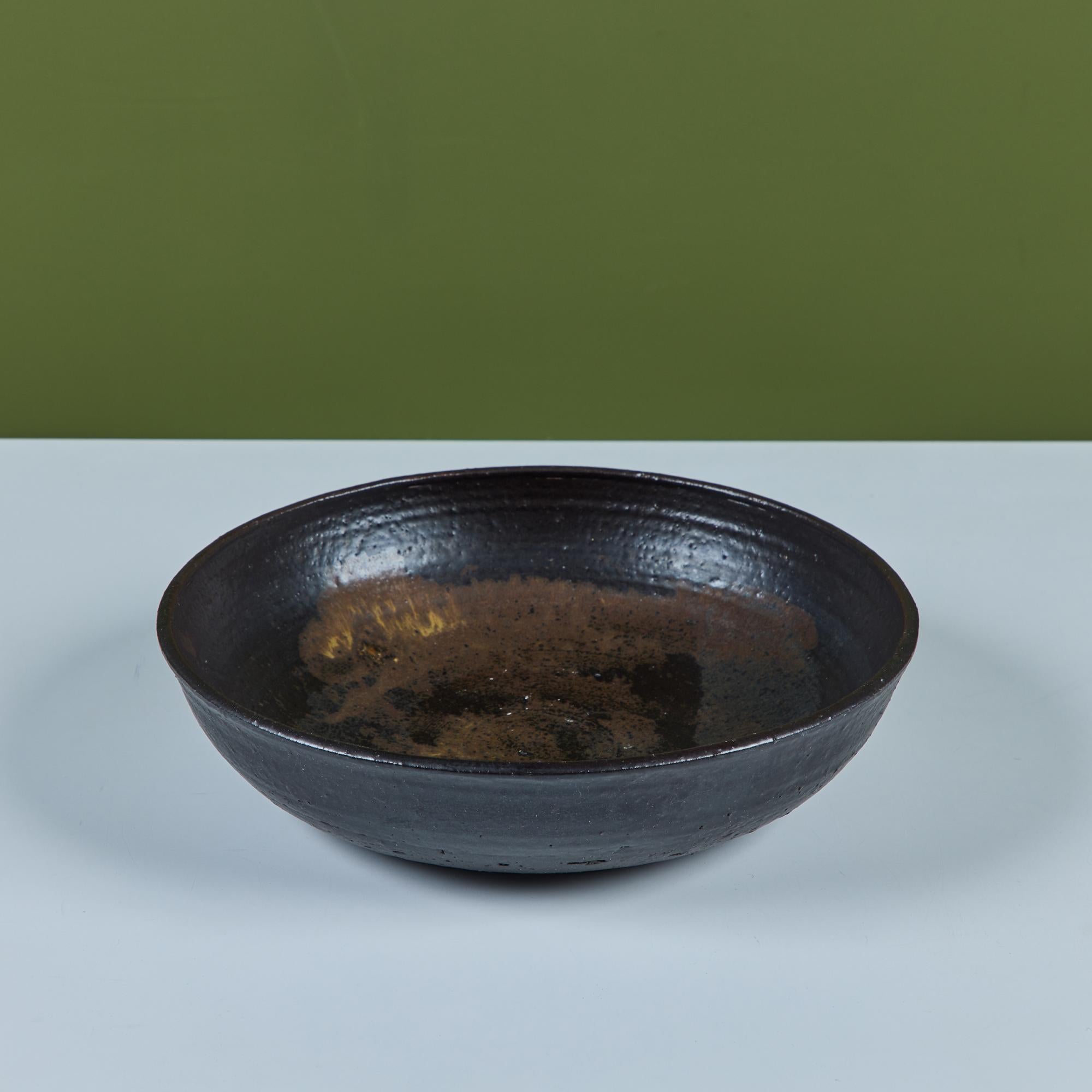 From famed Hawaiian ceramicist Toshiko Takaezu, a wheel thrown studio ceramic bowl features a dark brown glaze with tan brush strokes on the interior.

Dimensions
13.25