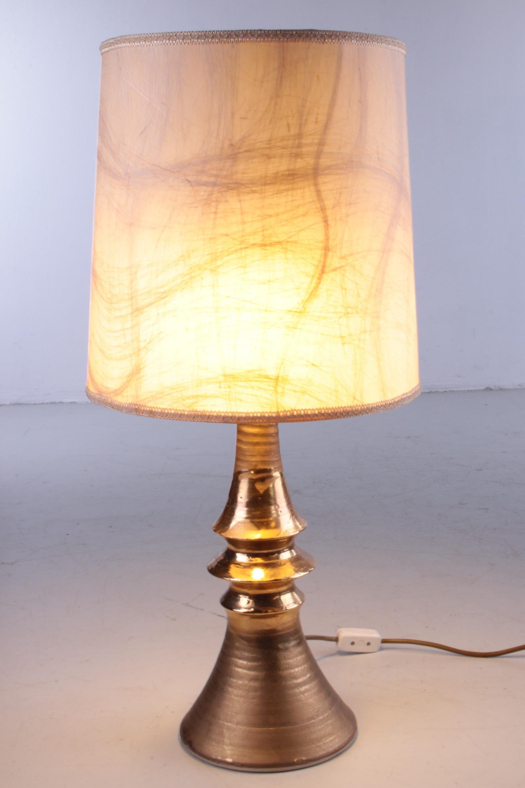 This is a beautiful golden table lamp made of ceramics presumably in Germany.

This lamp fits nicely in a modern or Hollywood Regency decor.

There is a switch on the cable with plug

This hood is original, but can of course be replaced by