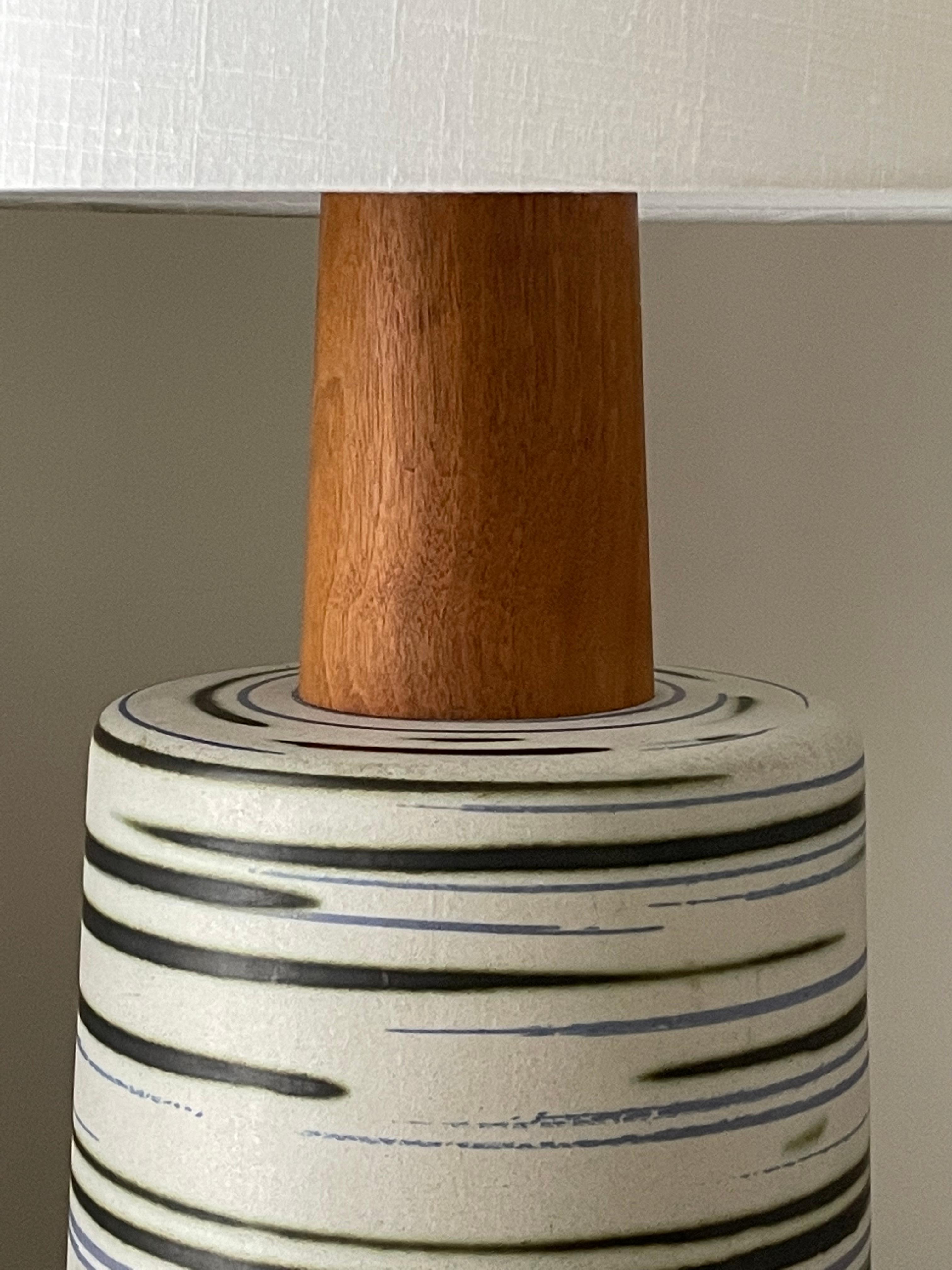 A truly monumental lamp by famed ceramicist duo Jane and Gordon Martz for Marshall Studios. This lamp features a massive ceramic body with big walnut neck and matching finial. Ceramic body is complete with a predominately white body with accents of