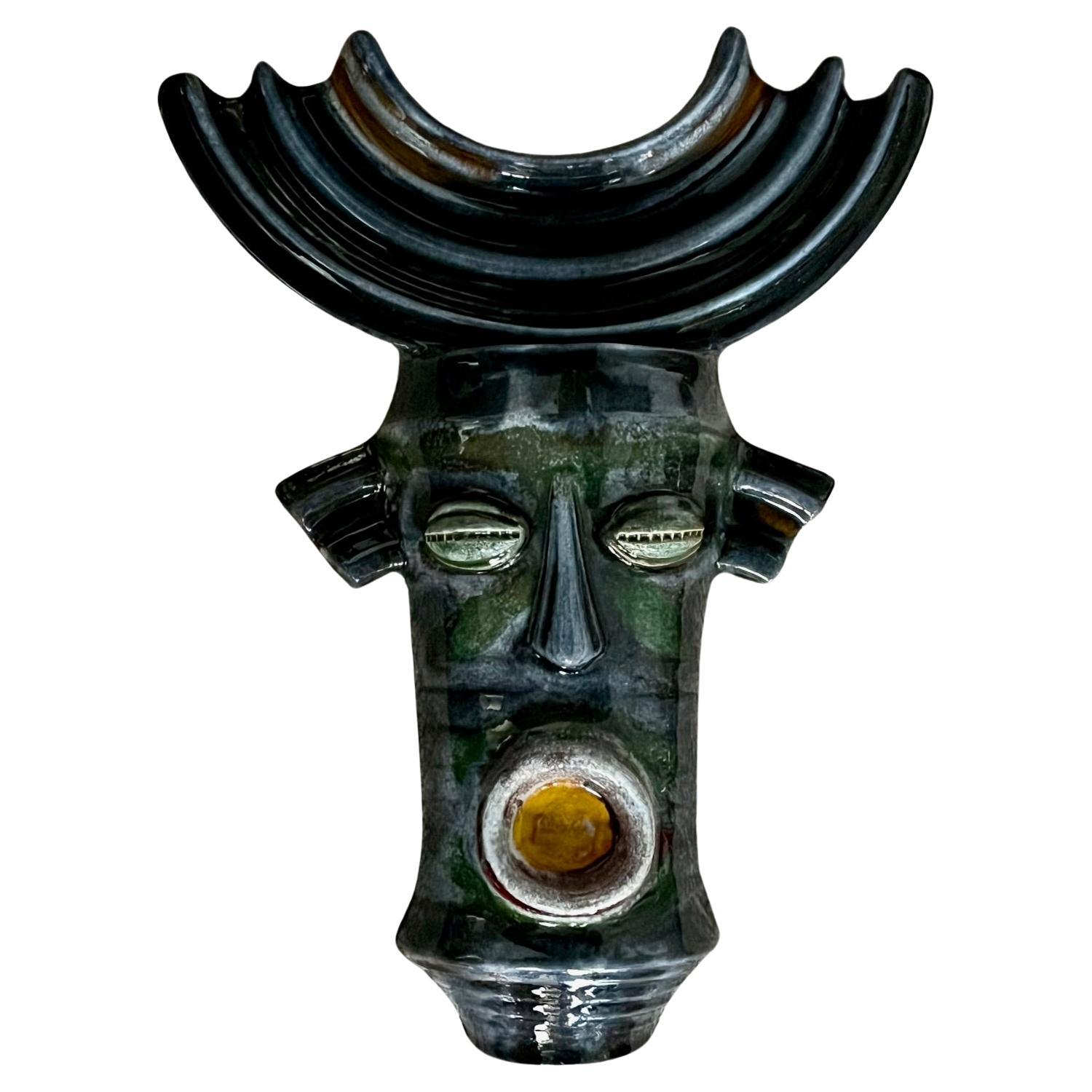 Large ceramic mask. Africanist inspiration.
Glazed ceramic in shades of dark green, blue, white and yellow. 
Boleslaw Danikowski ( 1928-1979 ) 
Danikowski's production is associated with Guillerme et Chambron furniture. 
Pieces by  