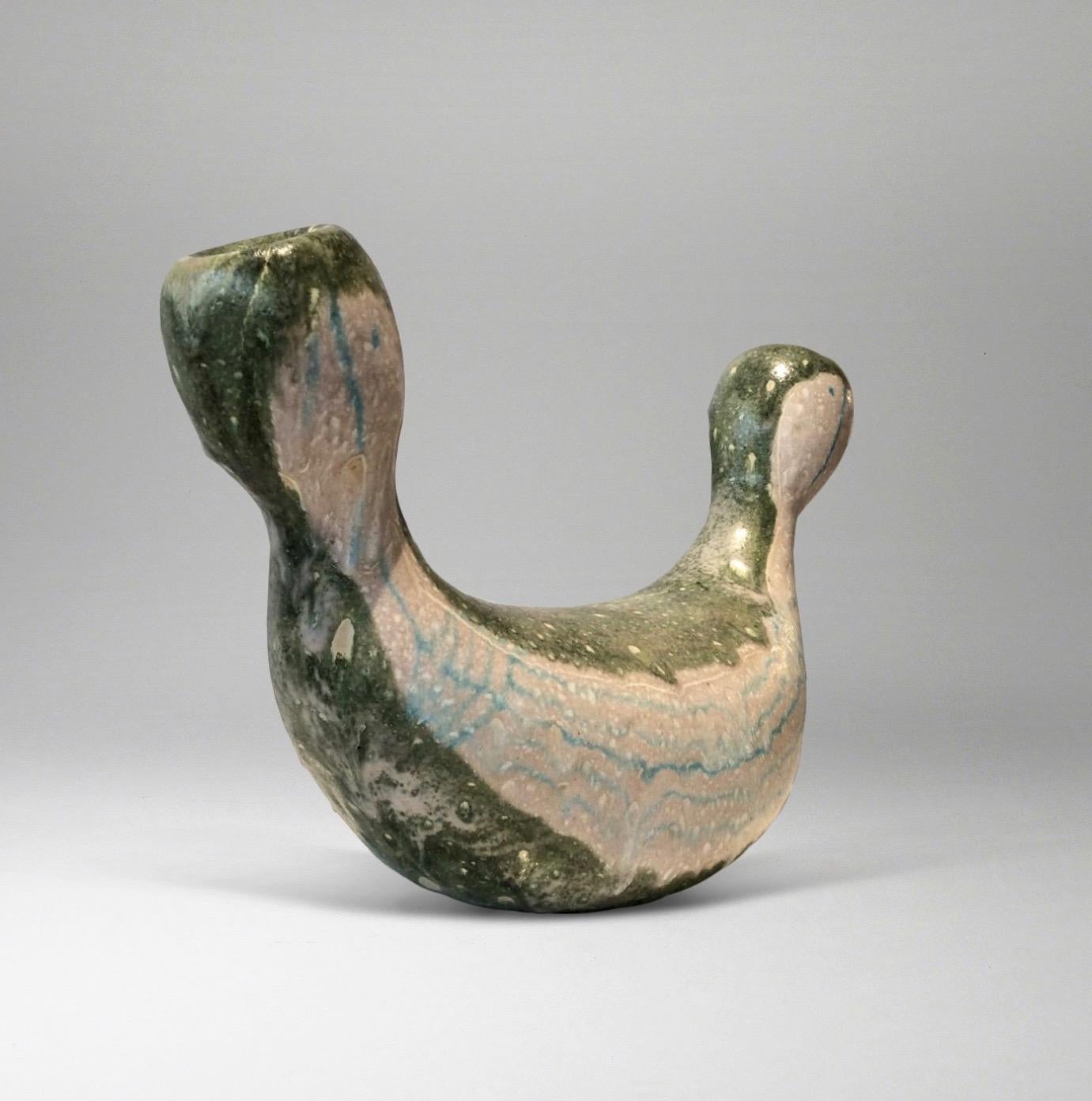 Rare and exceptional sculpture in sage green, turquoise, and ivory glazed ceramic. The curved form - unusual in Gambone's known works - terminates in faces sketched in turquoise (front and back). 
Glazed signature 'GAMBONE ITALY' with donkey symbol