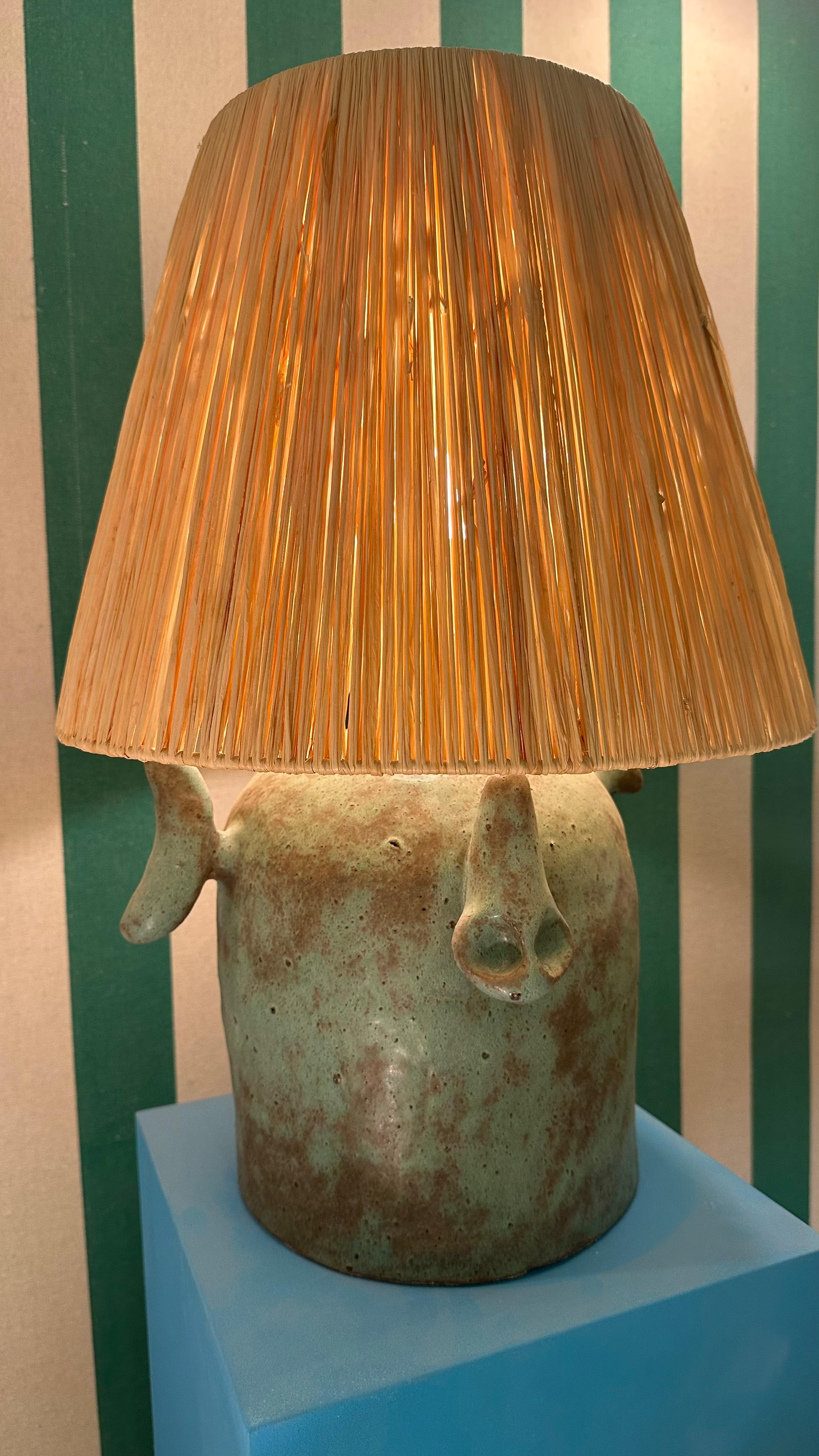 Construite à la main, cette lampe en céramique est fabriquée en terre cuite et émaillée par l'artiste, ce qui donne au corps de la lampe une patine de bronze. L'abat-jour en raphia a été réalisé à la main par l'artiste.

Tous les éléments sont la