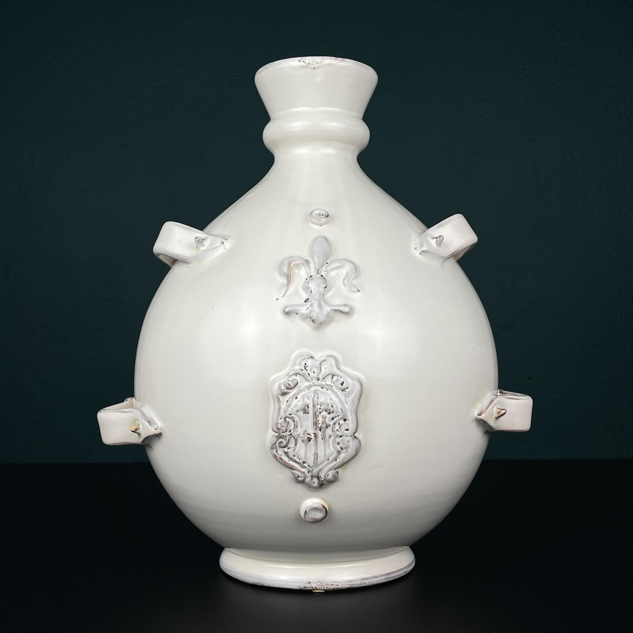 Grande vaso in ceramica smaltata di Gianfranco Ballerini realizzato in Italia negli anni '90.
Design e forma insoliti. La ceramica avorio smaltata, le 4 eleganti maniglie laterali, lo stemma in rilievo e il fleur-de-lis conferiscono all'oggetto un