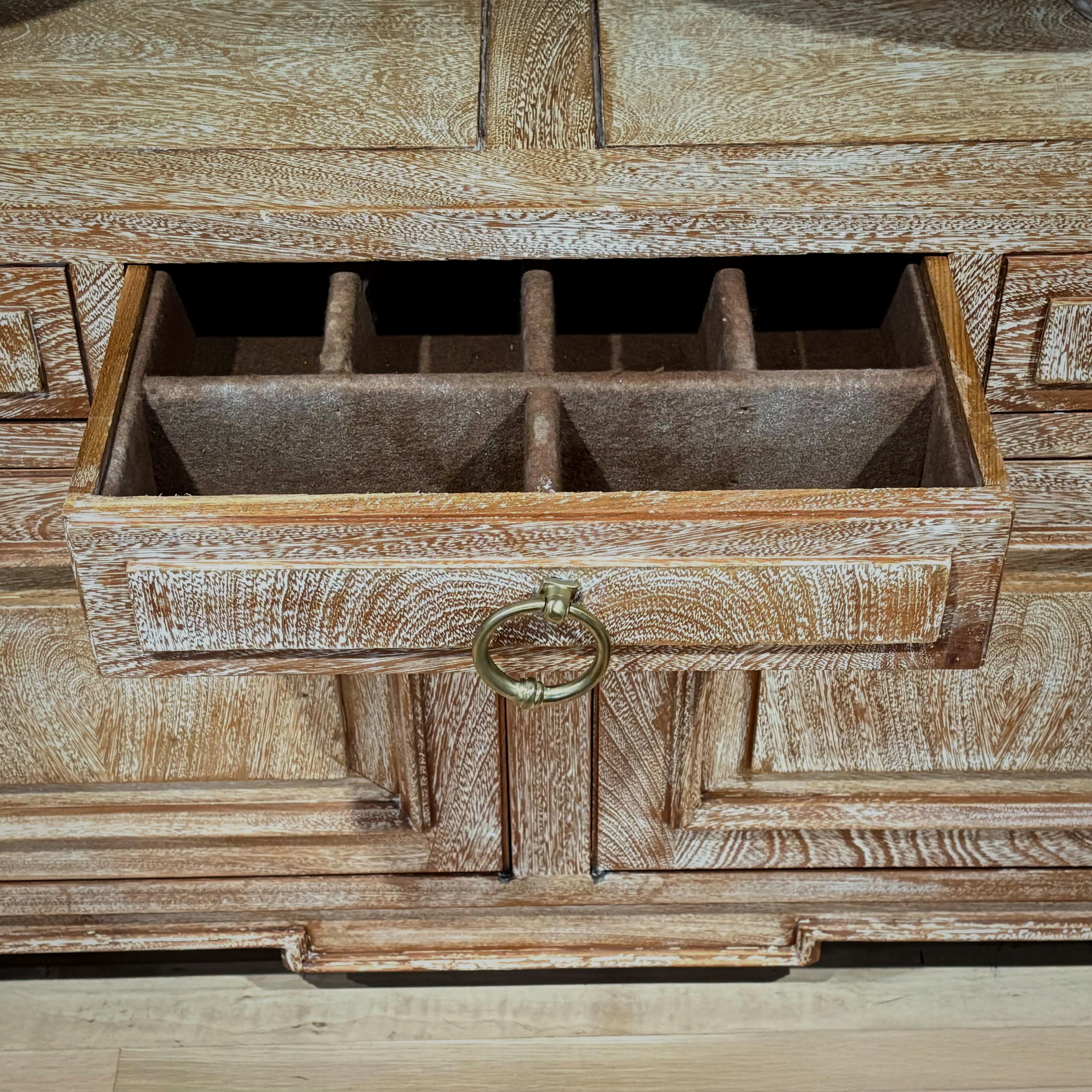 This spacious French sideboard from the 1950s is crafted in cerused oak, highlighting the natural grain with a soft, chalky finish.

Its balanced design features five drawers above four paneled doors, all with original bronze pulls. Offering
