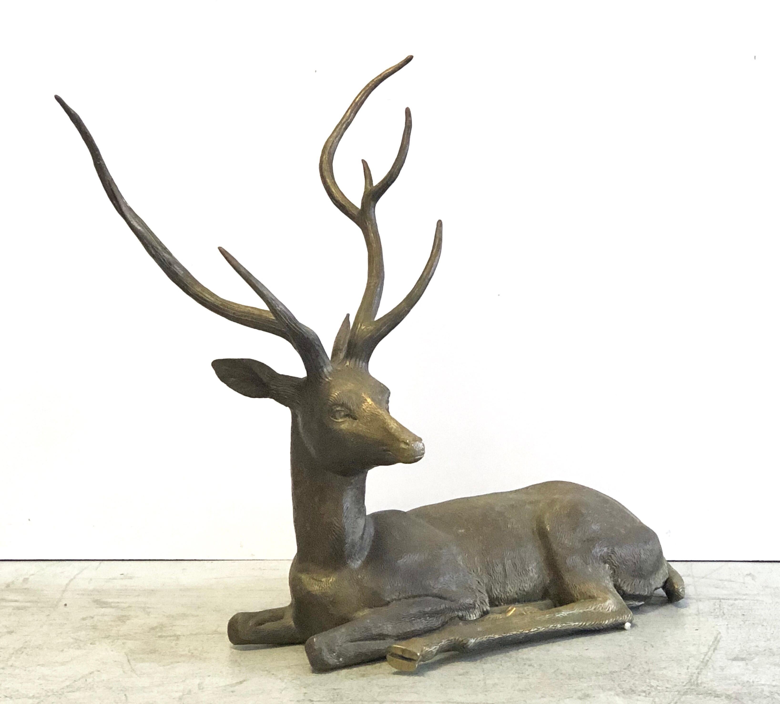 A large brass sculpture of a reclining deer. Striking pose and fine detail in the rendering.
