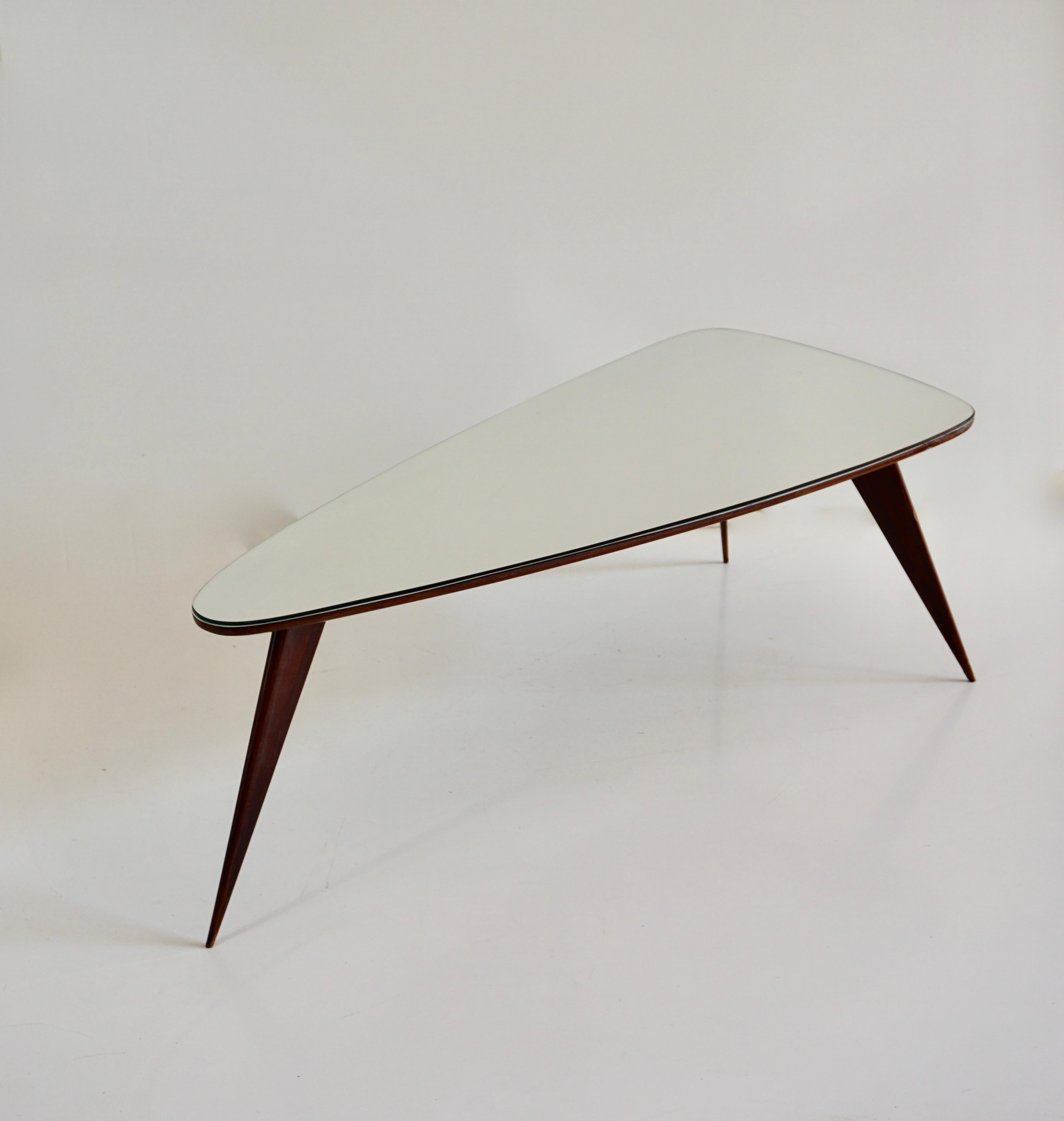 fine and elegant large  coffee table or occasional table 
designed by Arch. Cesare Lacca, 1950 
irregular shape, fine worked legs, three feet, mirrored and beveled top
walnut and mirror top 
Measures: h: 40 cm, 133 x 60; top height:4 cm 
very good