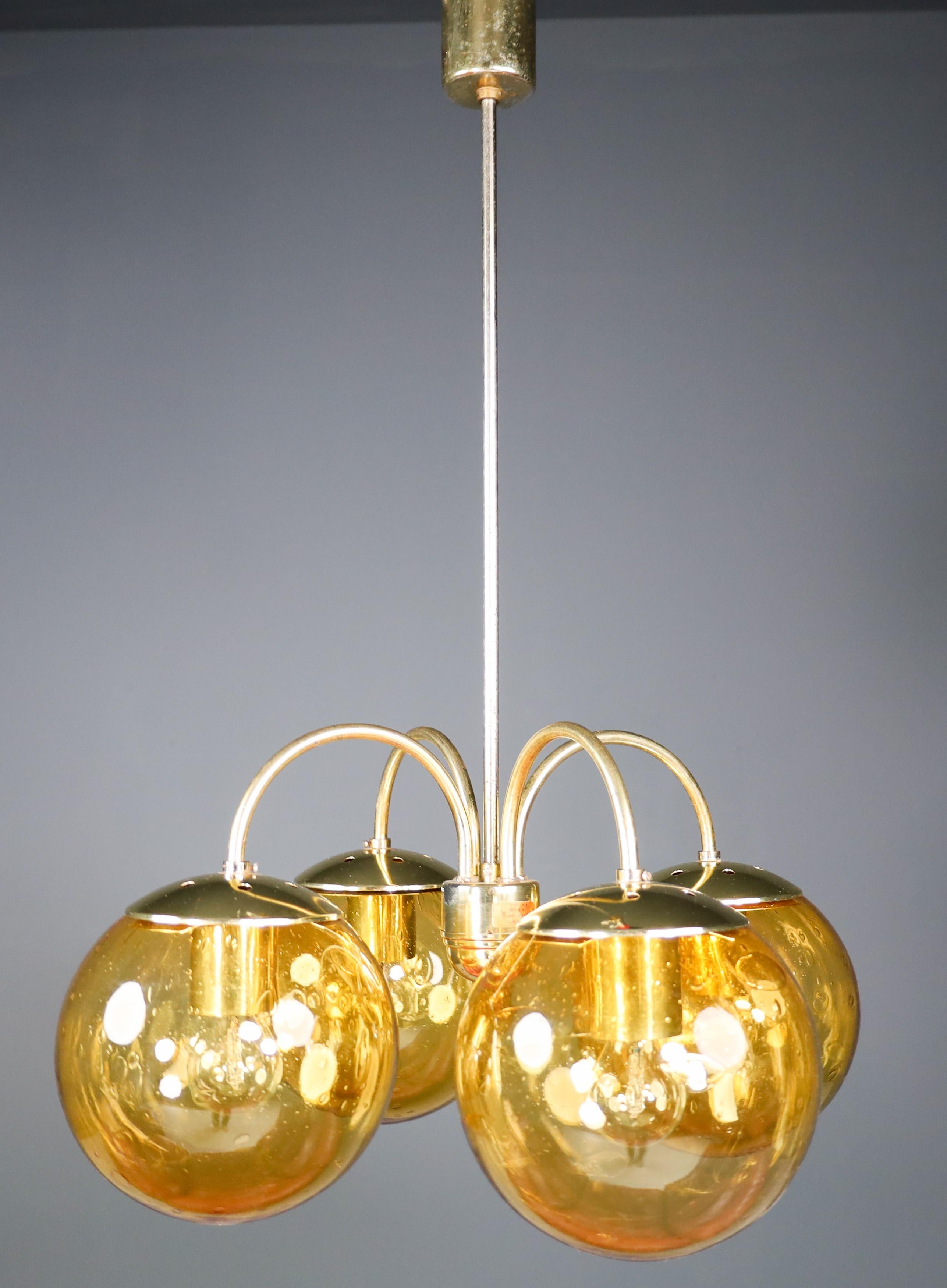 Large modern chandelier with four amber hand blown colored globes and brass, Europe, 1970s. The brass fixture beautifully combines with the amber colored glass. This chandelier will create an absolute stunning light partition by means of its large