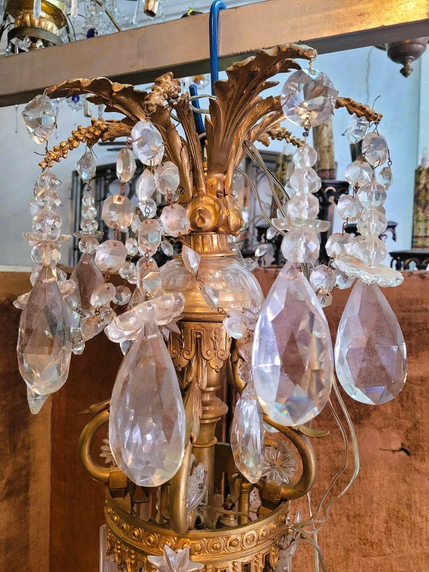 Large Napoleon III style gilded bronze chandelier, with rich bronze ornamentation (leaves, clusters of flowers) and crystal pendants (stars, knives, faceted pears, daggers)
Elegant chandelier lighting thanks to 10 candles to which is added interior