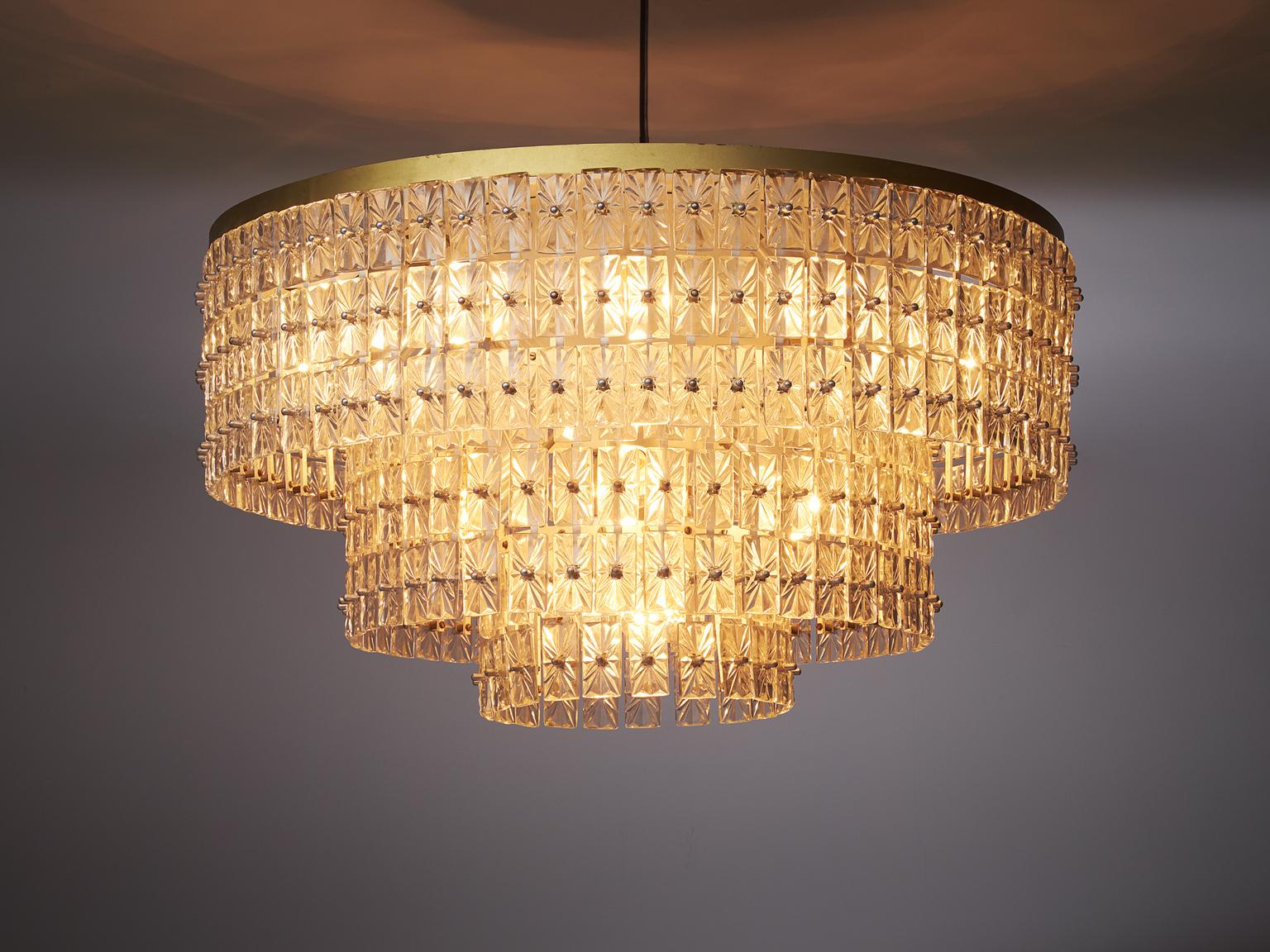 Extraordinary large chandelier in glass and brass, Austria, 1950s.

This wonderful ceiling lamp has a basic shape, built from a large amount of well detailed glass elements. It's mounted to a sincere construction, and beautifully enlightened by 21