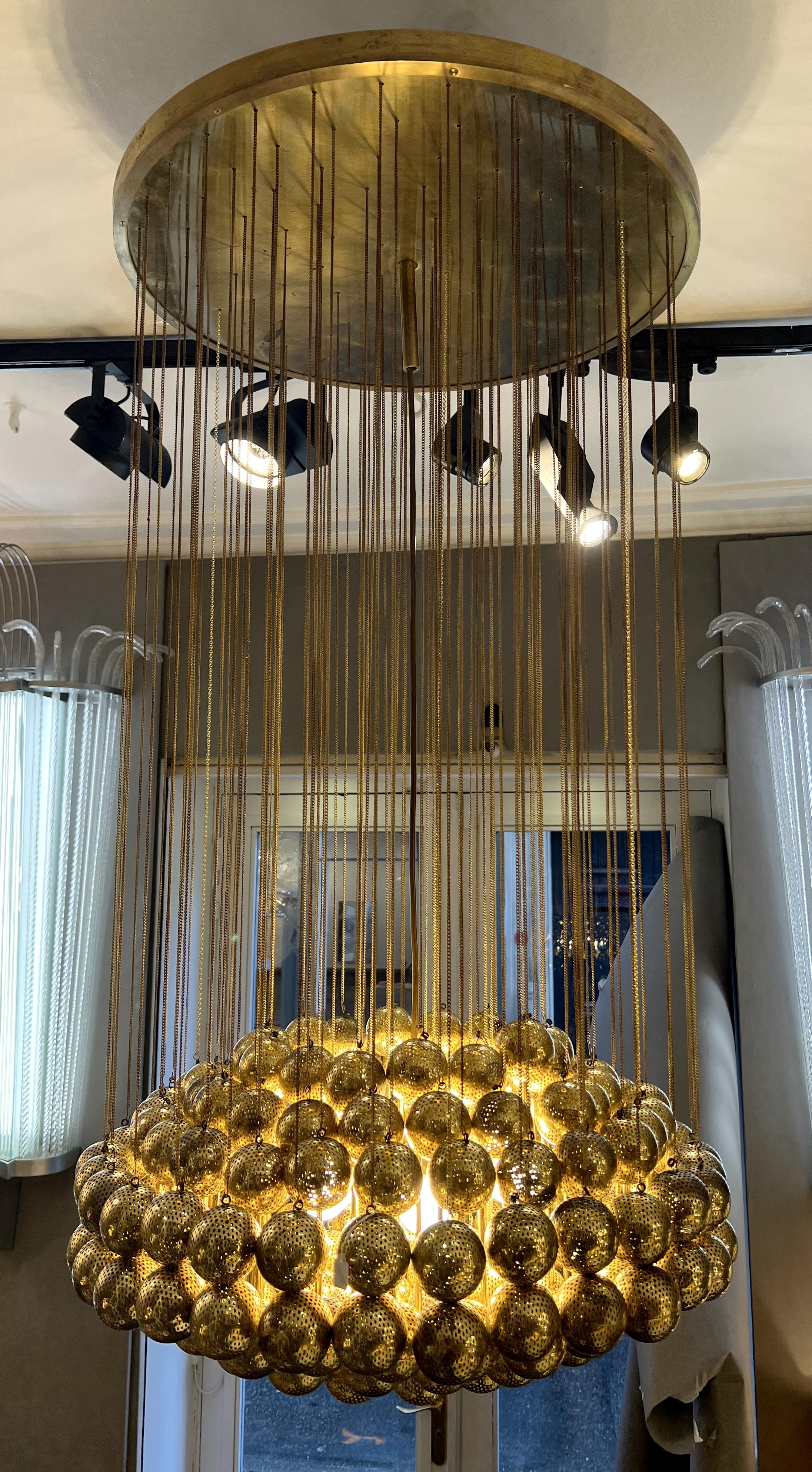 Rare suspension by Zero Quattro Milano, consisting of a multitude of perforated globes suspended from a ceiling light by chains. An electrical system bearing the Zero Quattro Milano label and supporting five bulbs is concealed high up in the center