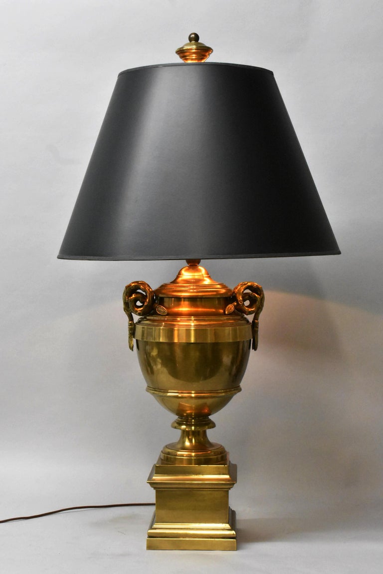 Heavy, large scale table lamp by Chapman. Solid brass urn shaped base with side ram horn handles. Oversize brass finial.
