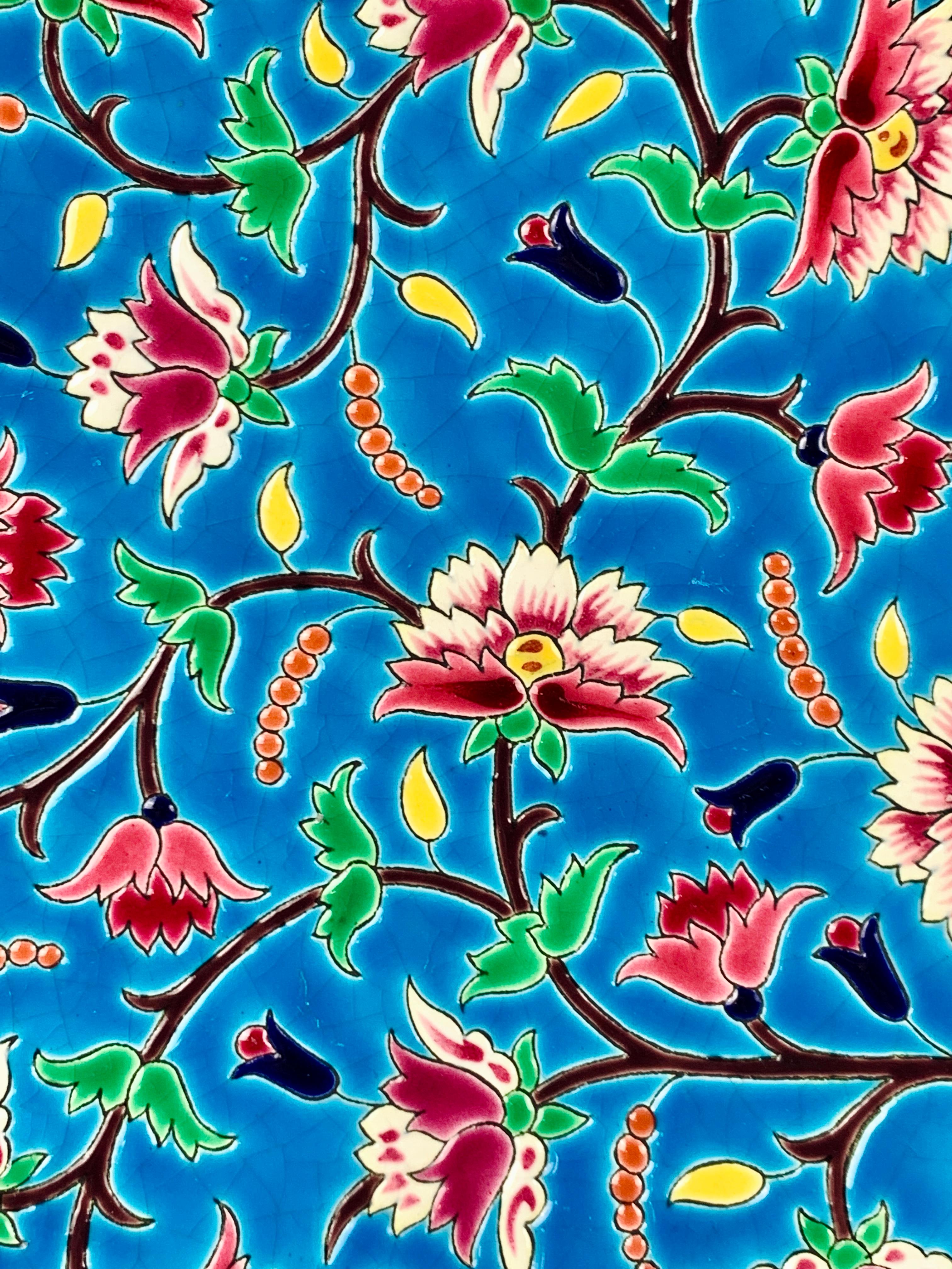 A hand-painted charger decorated with cloisonné enamels* in a brilliant combination of the Art Deco and Chinoiserie styles. 
The colors are splendid: the bright turquoise-blue ground is filled with pink and purple flowers, green and yellow leaves,