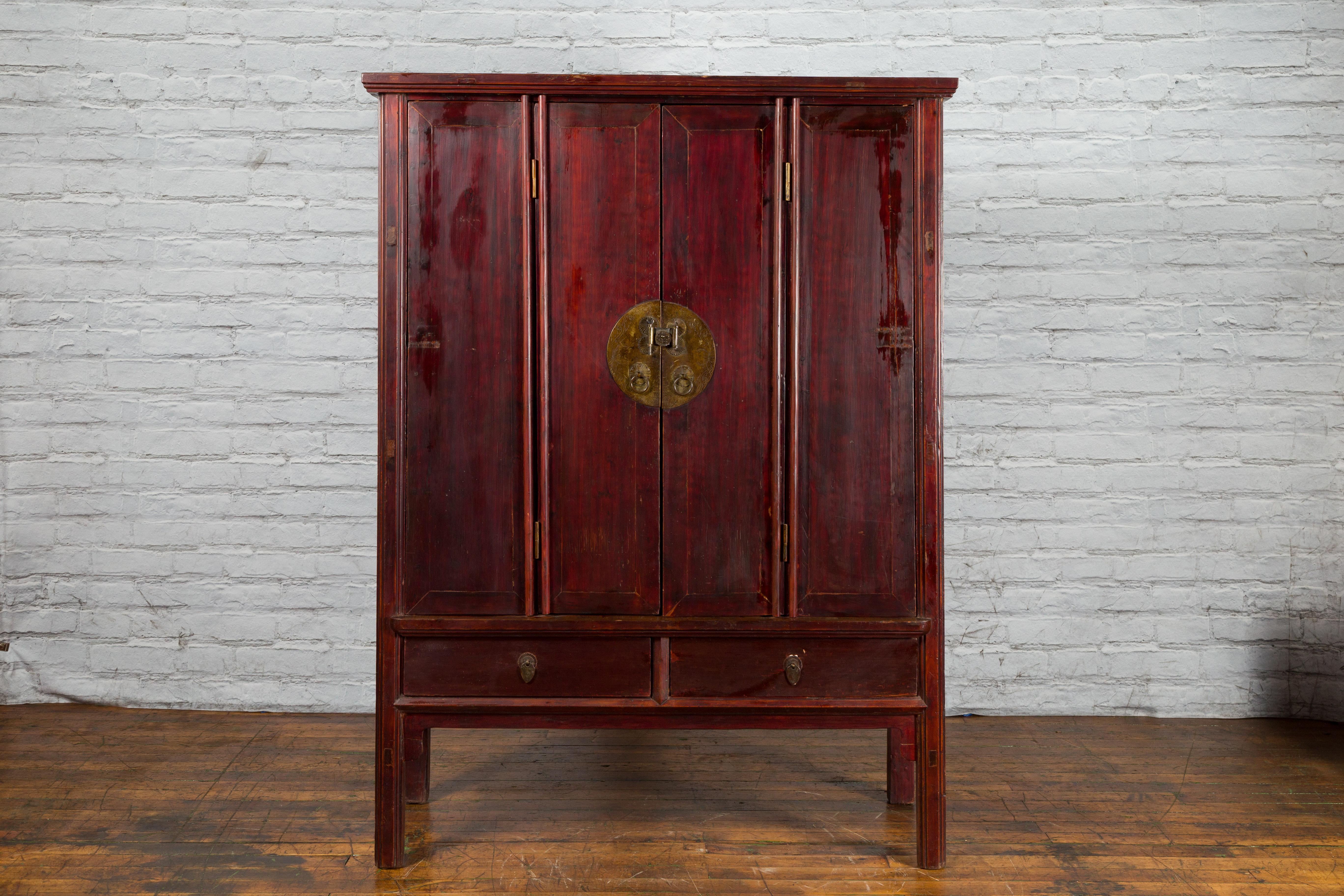 A large Chinese Qing Dynasty period cabinet from the 19th century with accordion doors and drawers. Created in China during the Qing Dynasty, this lacquered cabinet features a tapering silhouette complimented by a dark reddish brown finish. The