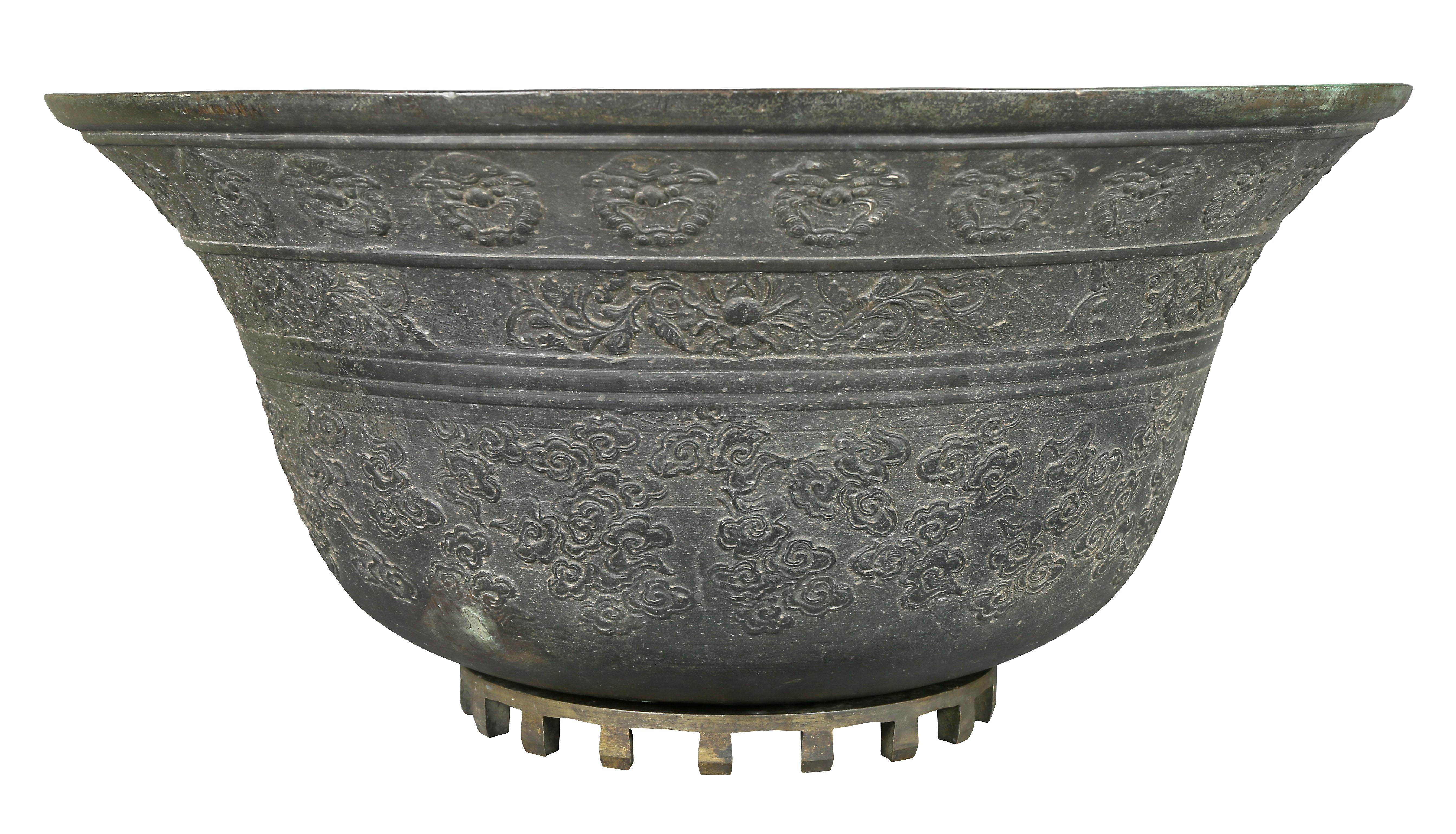 Bell shape with overall cast decoration featuring masks, clouds and lotus decoration. Later separate stand.