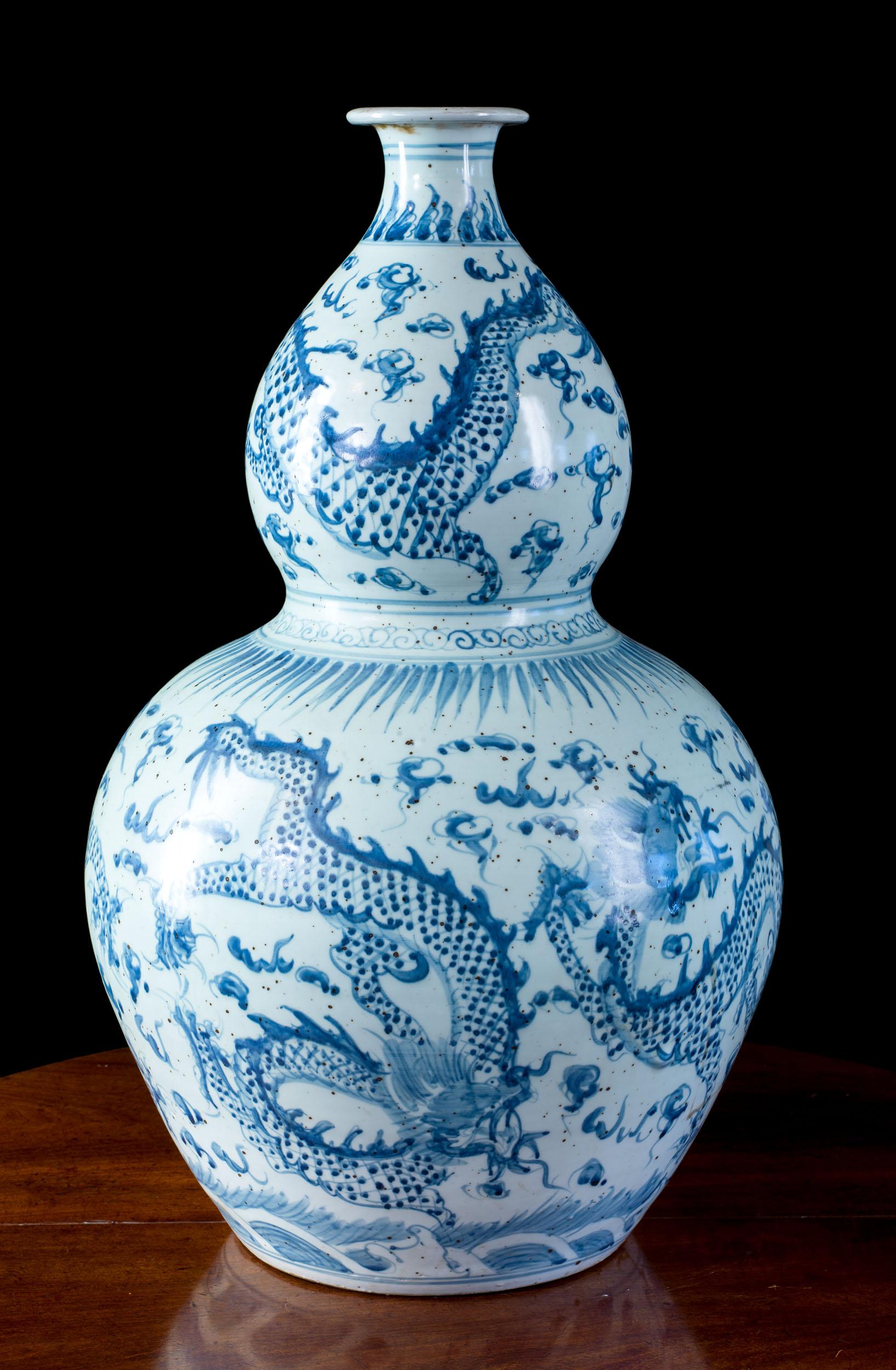 An antique Chinese blue and white calabash vase. The vase is hand painted with the 'dragon chasing the flaming pearl' motif. Far from the fearsome representation of the dragon in Western Art, in Chinese iconography, the dragon is seen as a