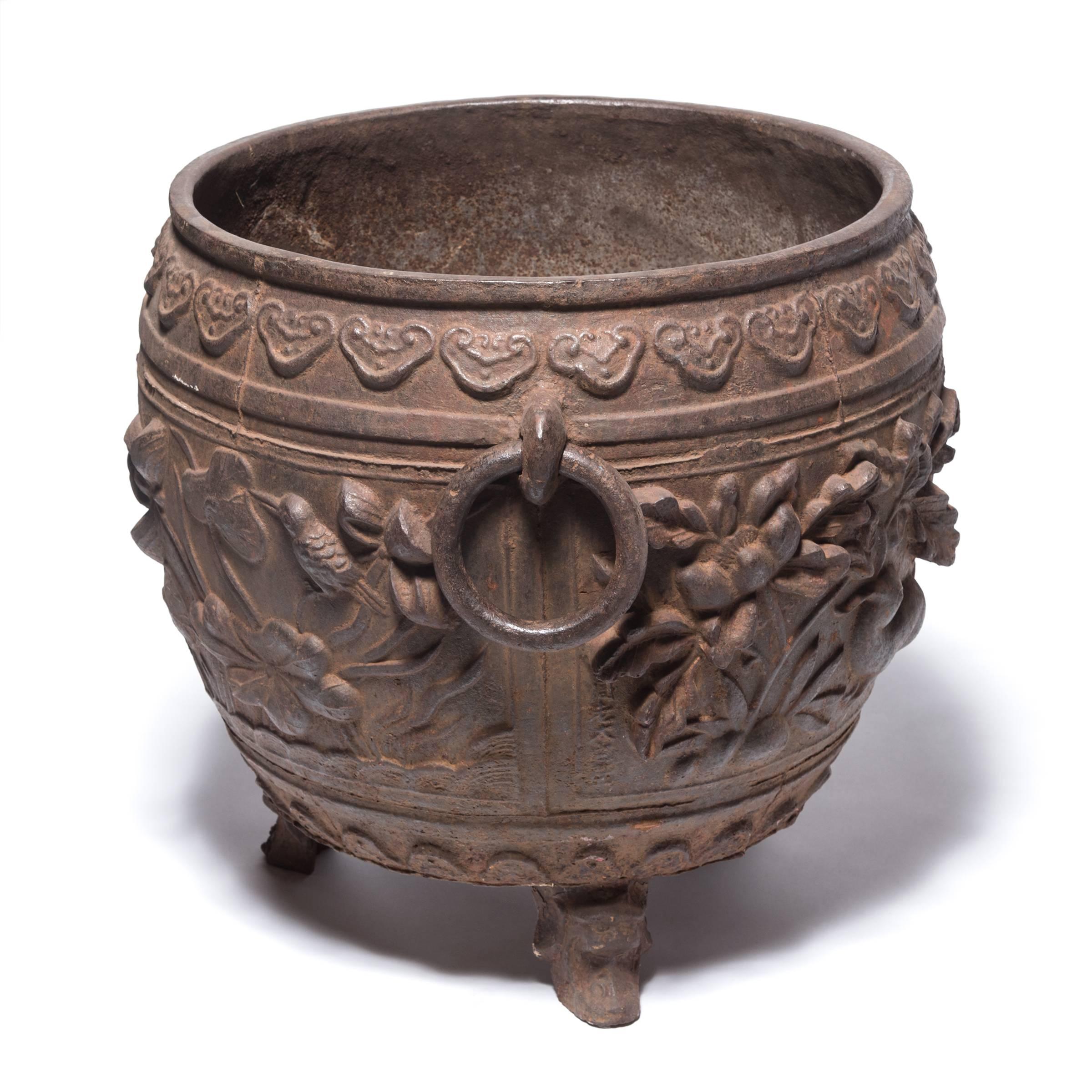 China was the earliest known civilizations to work with cast iron, first appearing thousands of years ago during the illustrious Zhou dynasty. Textured with floral motifs in high relief and balanced on tripod feet, this contemporary urn references