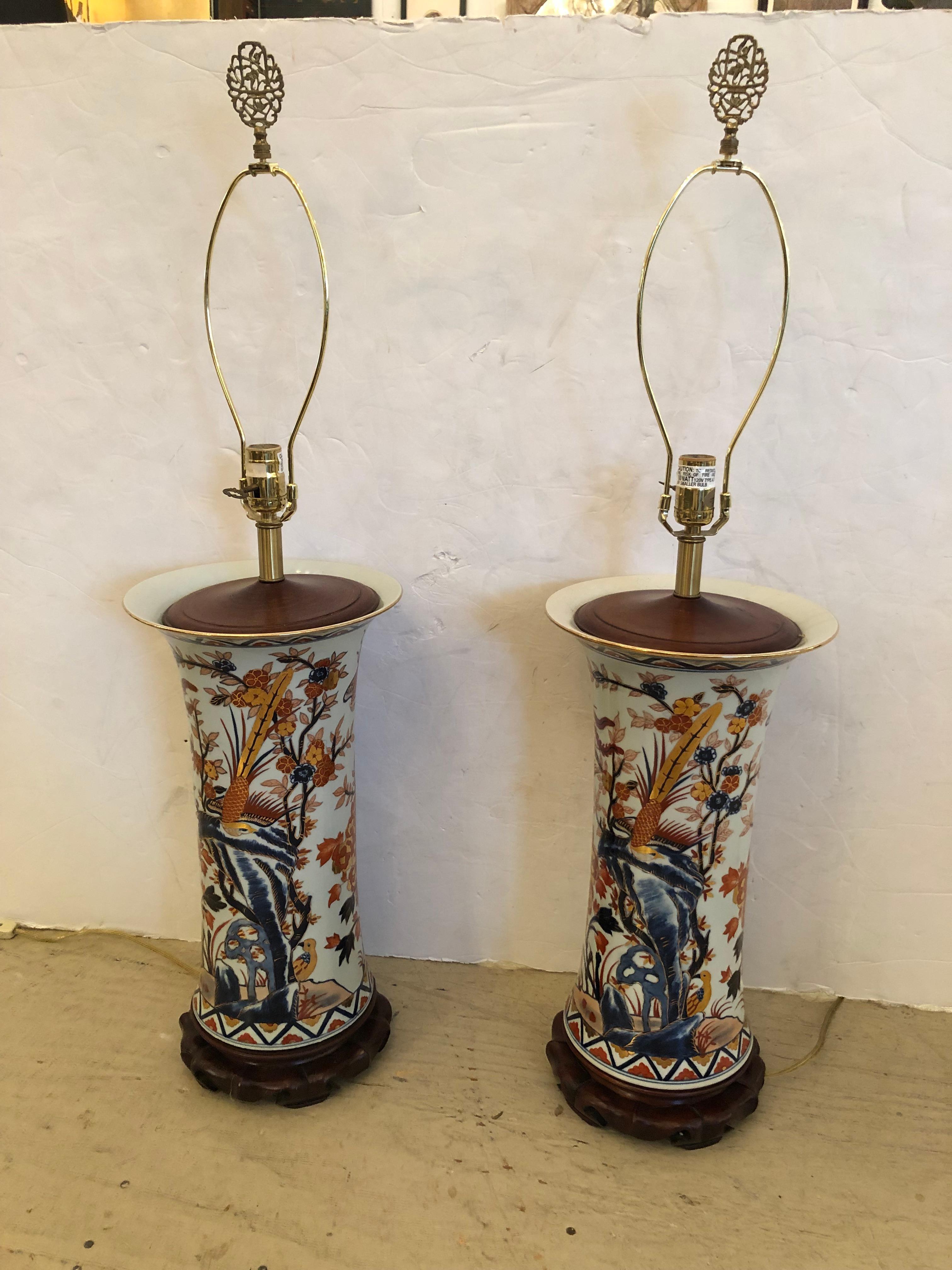 Large impressive and beautiful pair of vintage cylindrical Chinese table lamps having stunning decoration with birds and foliage in navy blue, burnt orange and gold against a white background.  Handsome dark wood bases and custom contemporary