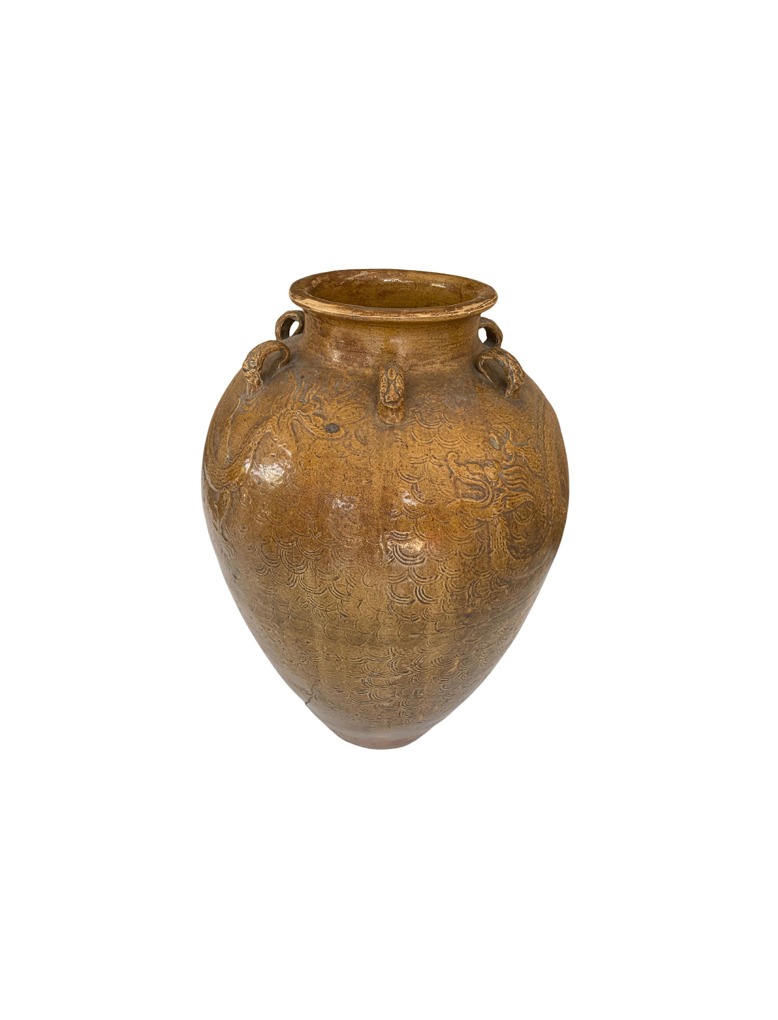 This Chinese Ceramic Jar features a Brownish / Yellow Glaze. In addition tiger medallions in the shape of loops wrap around the Jar’s shoulder. These were used to secure the lid to the jar and prevent the contents from leaking. Jars such as these