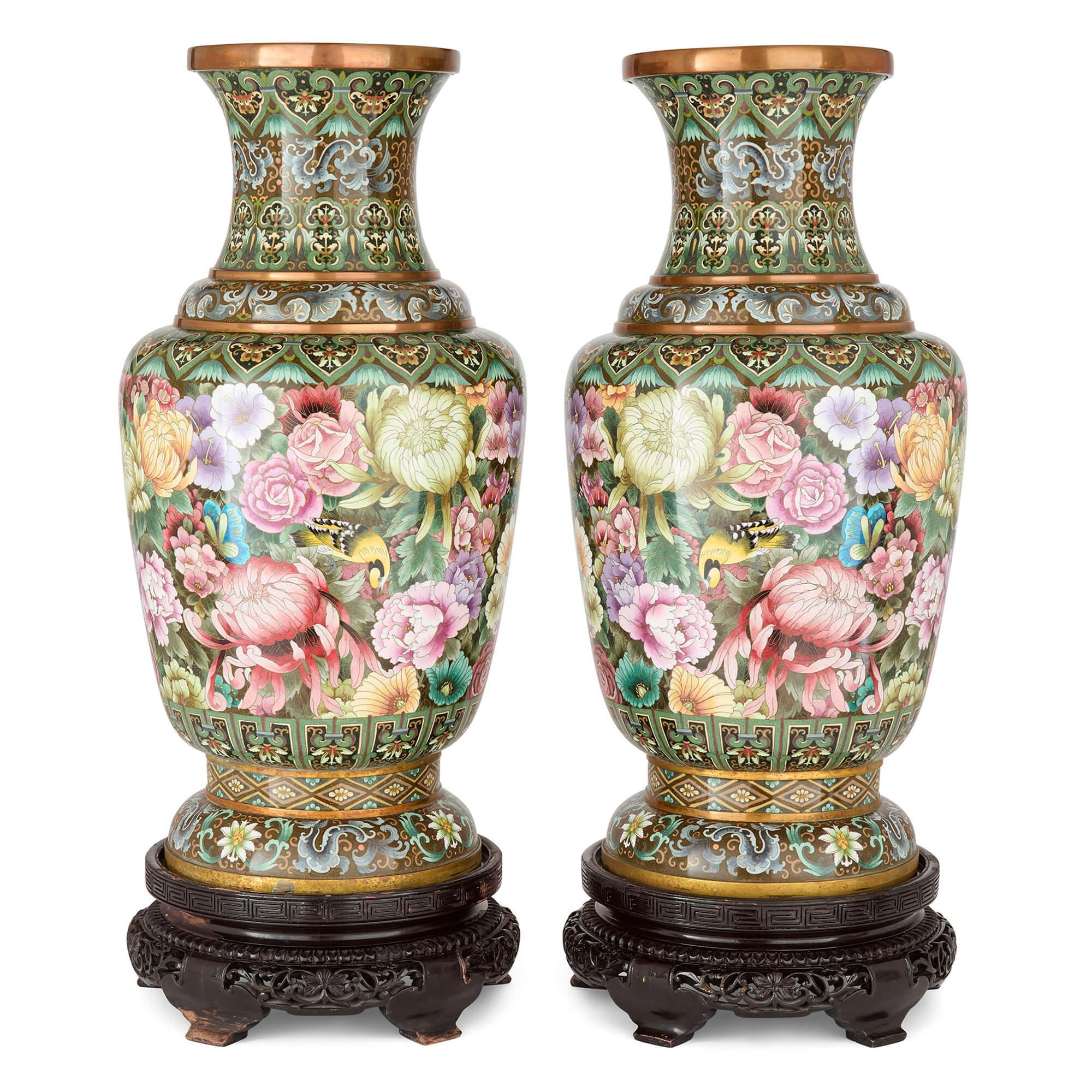 Large Chinese Cloisonné Enamel Floral Vases Wood Stands 
Chinese, 20th Century 
Vases: Height 78cm, diameter 36cm
Bases: Height 15cm, diameter 38cm
Overall: Height 93cm, diameter 38cm

This striking pair of cloisonné enamel vases originates from