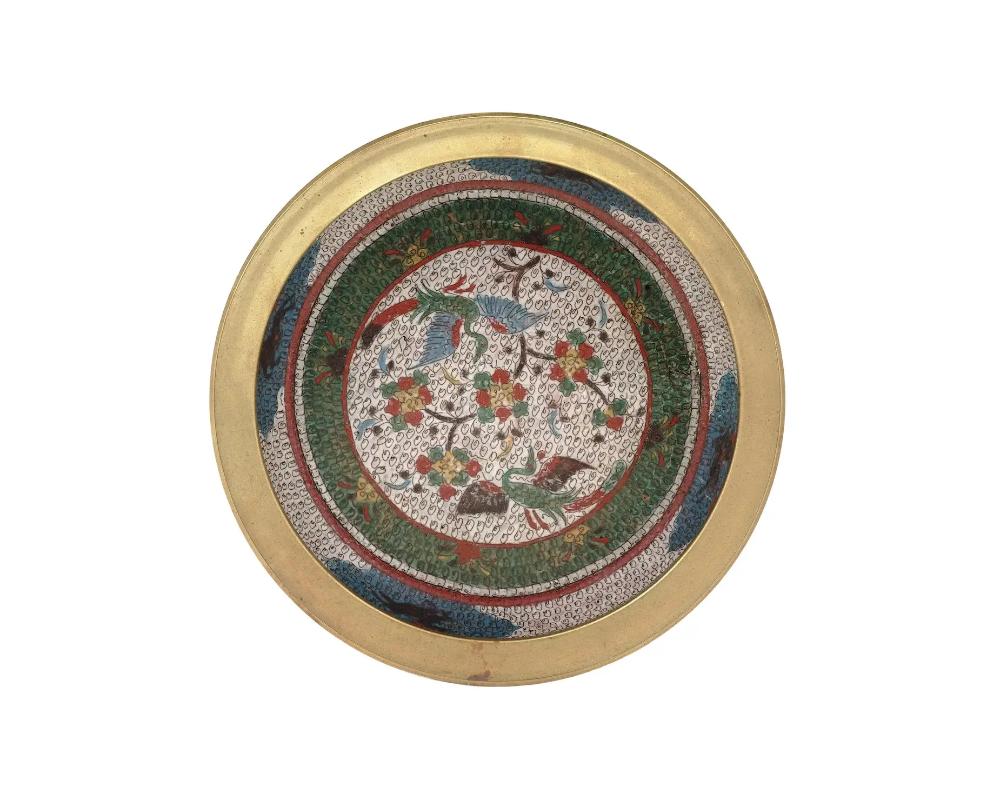A large antique Chinese Meiji Era bronze and enamel charger. Circa: late 19th century to early 20th century. The charger is enameled with polychrome images of birds with in a garden with blossoming flowers surrounded by floral, foliage, and cloud