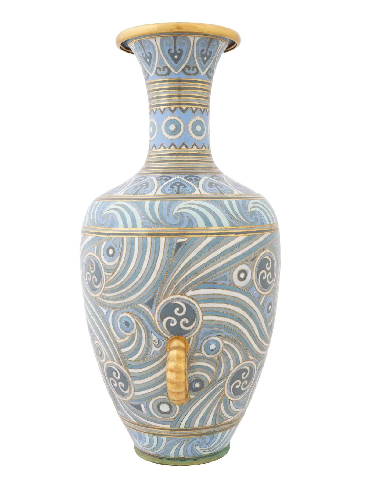 A large Chinese cloisonne enamel vase adorned with a blue, gray, and white geometric design. The vase has a narrow neck and a flared opening with a gilt interior. There are small curved gilt handles lower, near the base. The body of the vase is