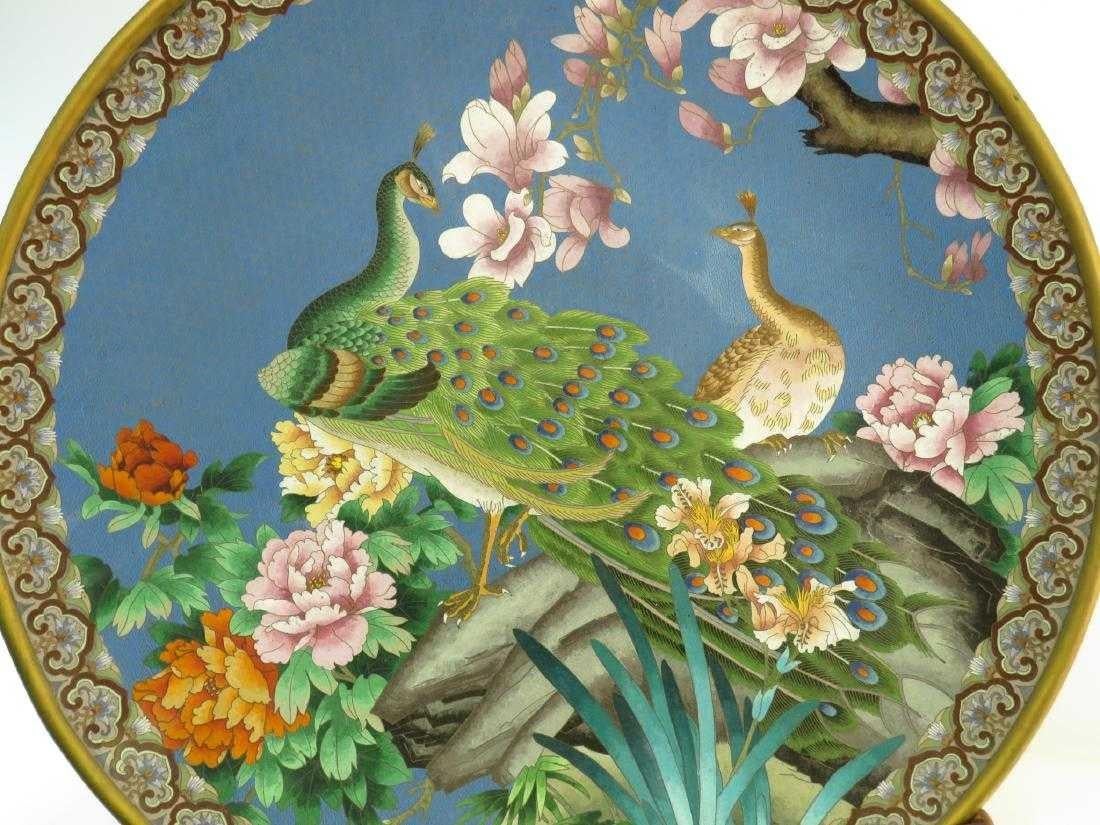 Huge Chinese cloisonné charger depicting two peacocks among flowers on original hand-carved wood Stand. Decorated on underside as well. Measures a total of 30.5