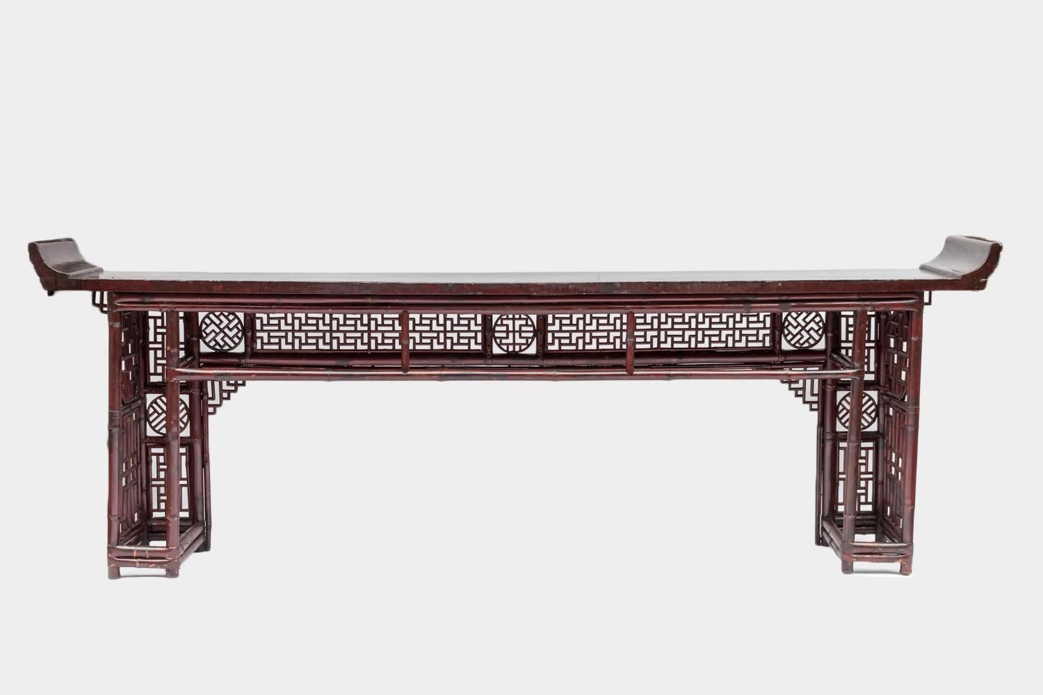 Large Chinese console in red lacquered bamboo standing on two rectangular shaped legs constituted by vertical sticks linked together. Apron and legs with a decor of geometrical Chinese openwork motifs.
Red lacquered wood tray in a pagoda